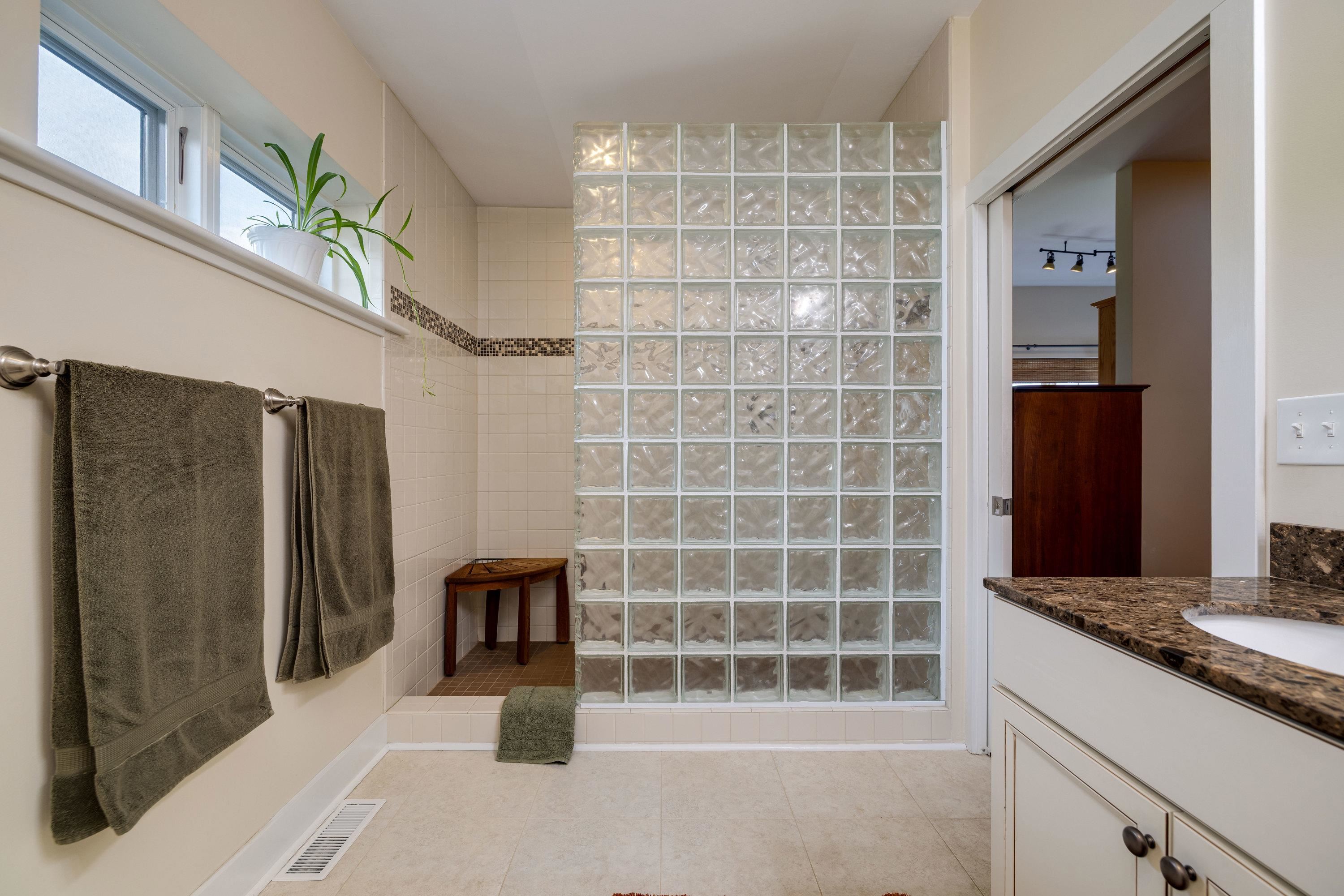 This full bathroom features dual vanities, tile shower, tile flooring, and lots of storage cabinetry.