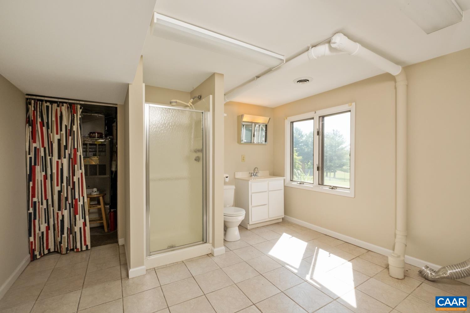 This is the full bathroom located in the basement.  The utility closet is beyond the curtain.