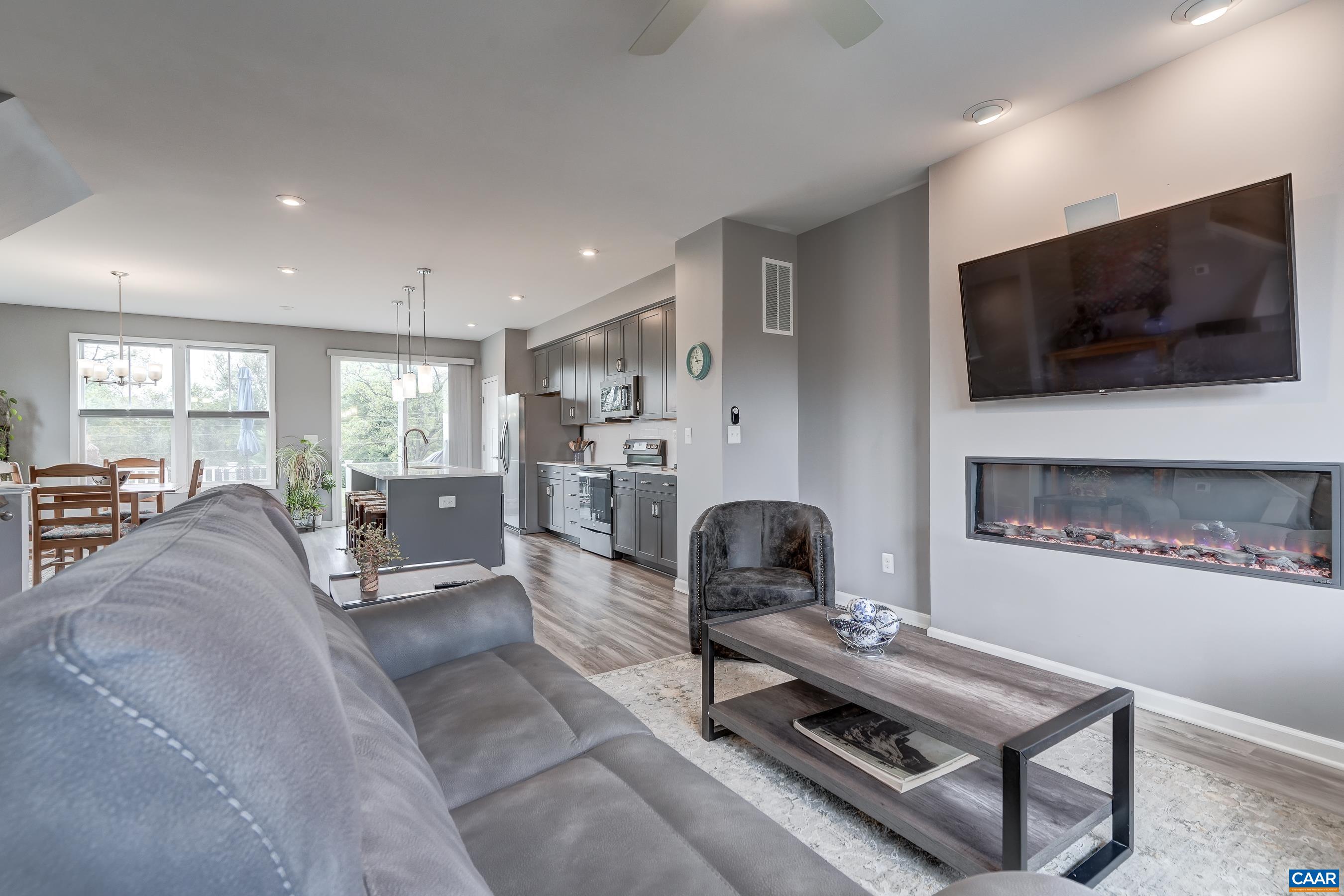 Main level features an open floor plan with large living room featuring electric fireplace and ceiling fan.