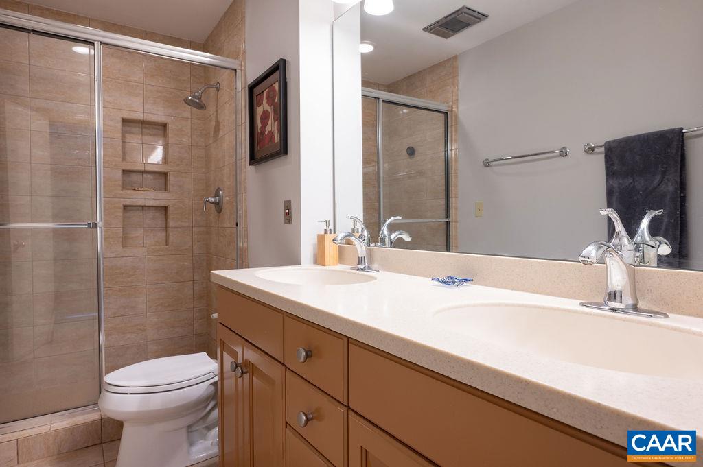 Attached primary bath has double vanities, tiled shower and floor.