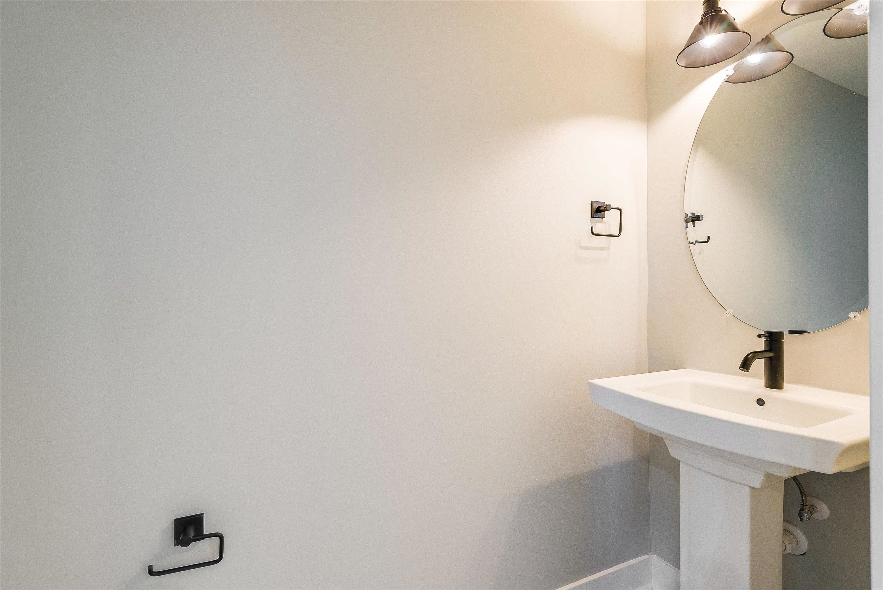 Half bath on the main level features pedestal sink and tile floors Half bath on the main level features pedestal sink and tile floors