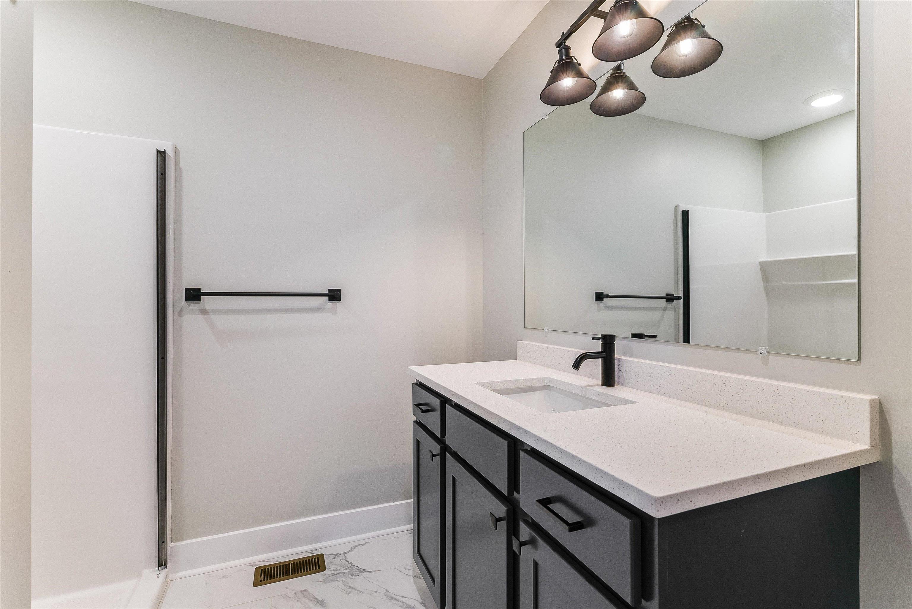 Primary bath of our model home featuring an upgraded quartz countertop, large single vanity and walk in shower with optional glass door upgrade. Primary bath of our model home featuring an upgraded quartz countertop, large single vanity and walk in shower with optional glass door upgrade.