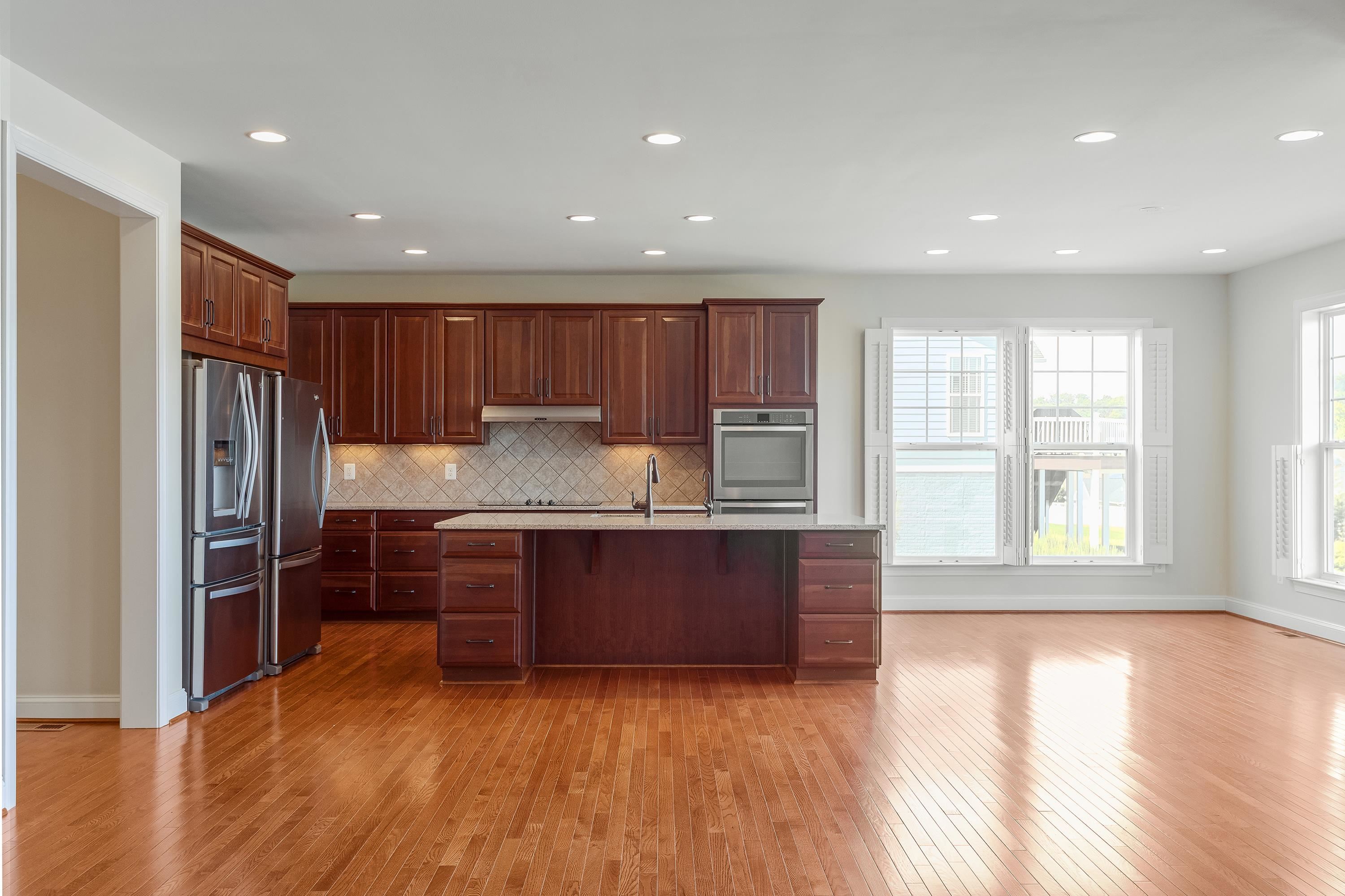 This open concept kitchen features many upgrades throughout.  A few include stainless steel appliances, two refrigerators, recessed lighting, granite counter-tops, hardwood flooring, breakfast bar, and plenty of space for an additional dining space.