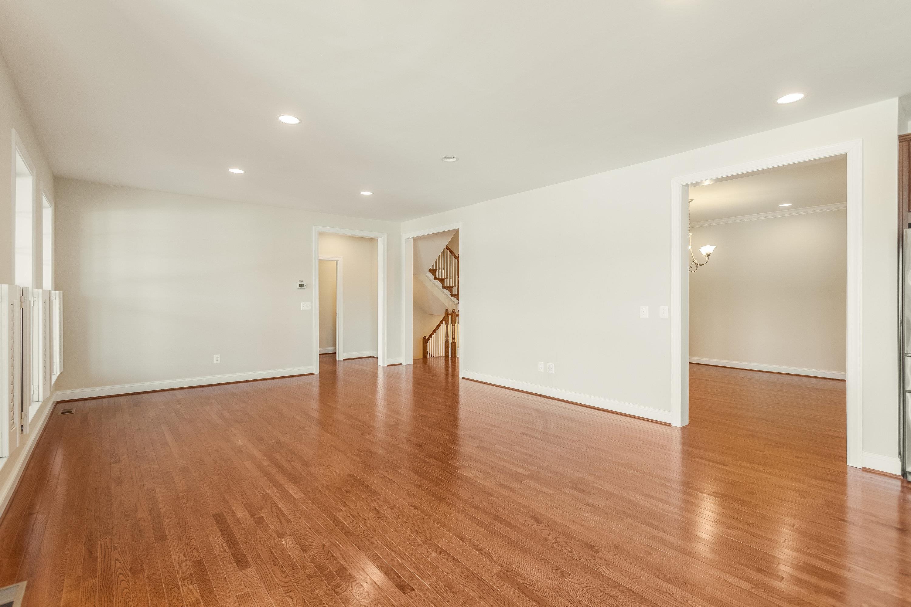 This very expansive living room space features hardwood floors, multiple large windows, elevated ceilings, recessed lighting, and plenty of space for gathering with friends and family.