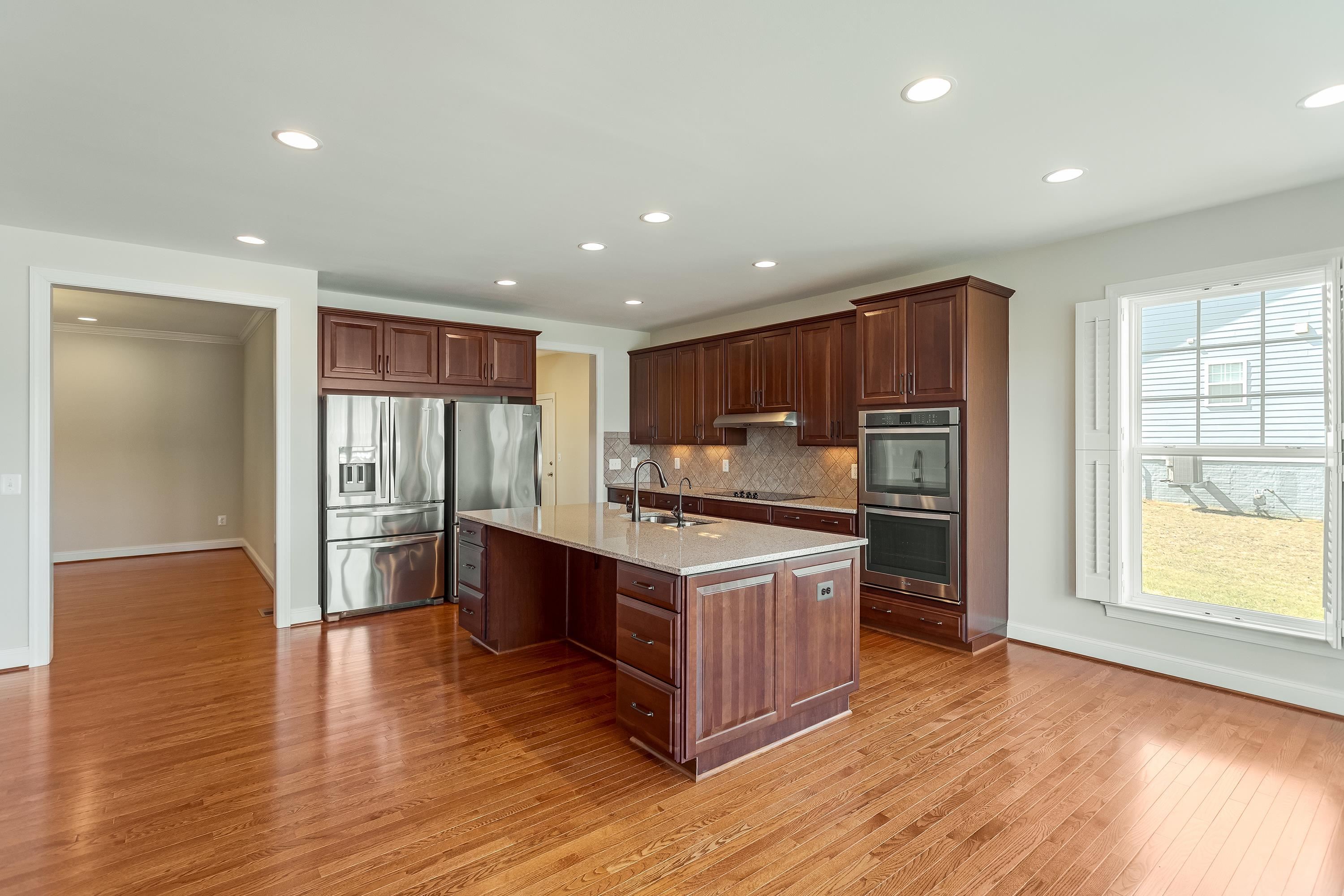 This open concept kitchen features many upgrades throughout.  A few include stainless steel appliances, two refrigerators, recessed lighting, granite counter-tops, hardwood flooring, breakfast bar, and plenty of space for an additional dining space.