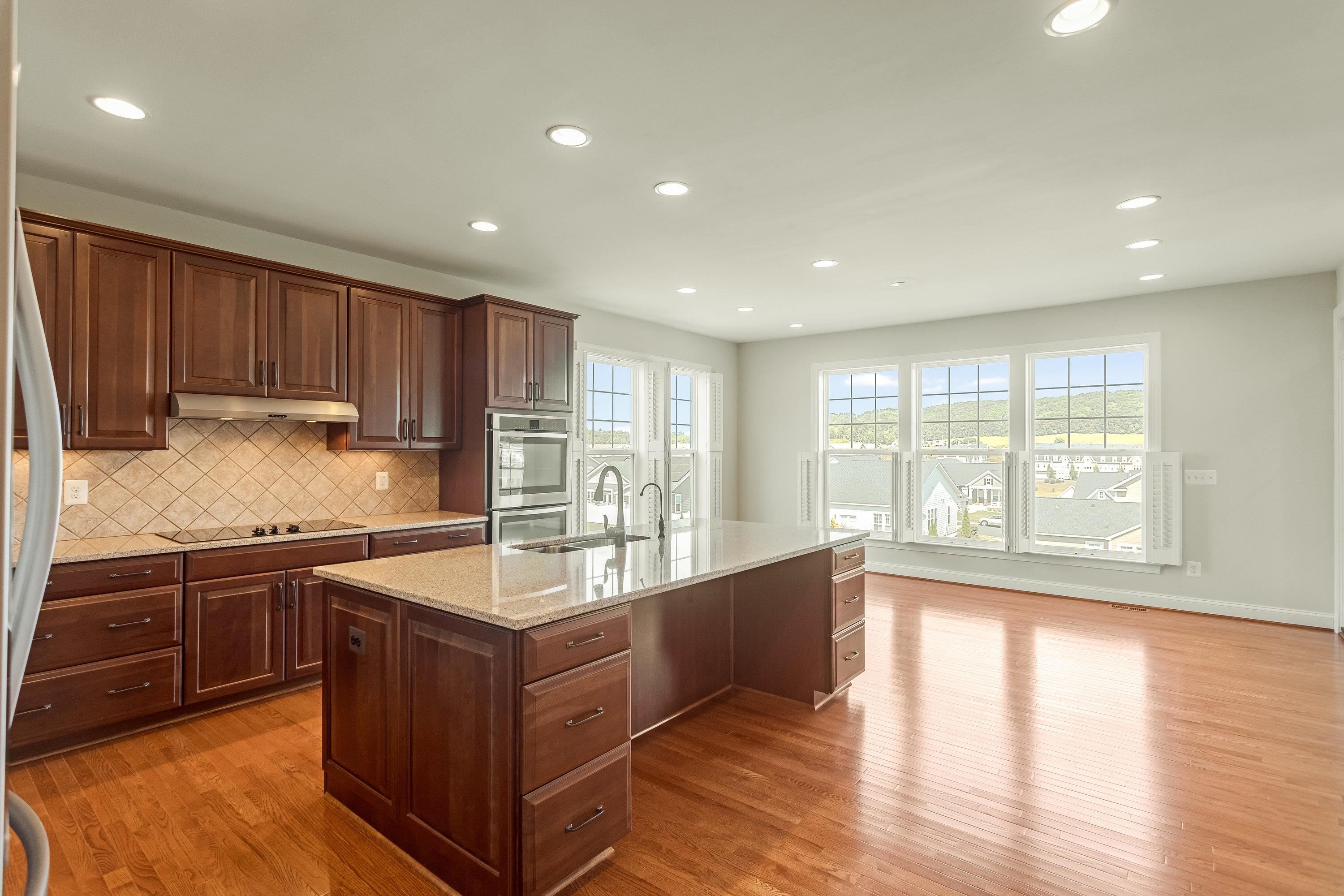 This open concept kitchen features many upgrades throughout.  A few include stainless steel appliances, two refrigerators, recessed lighting, granite counter-tops, hardwood flooring, breakfast bar, and plenty of space for an additional dining space.