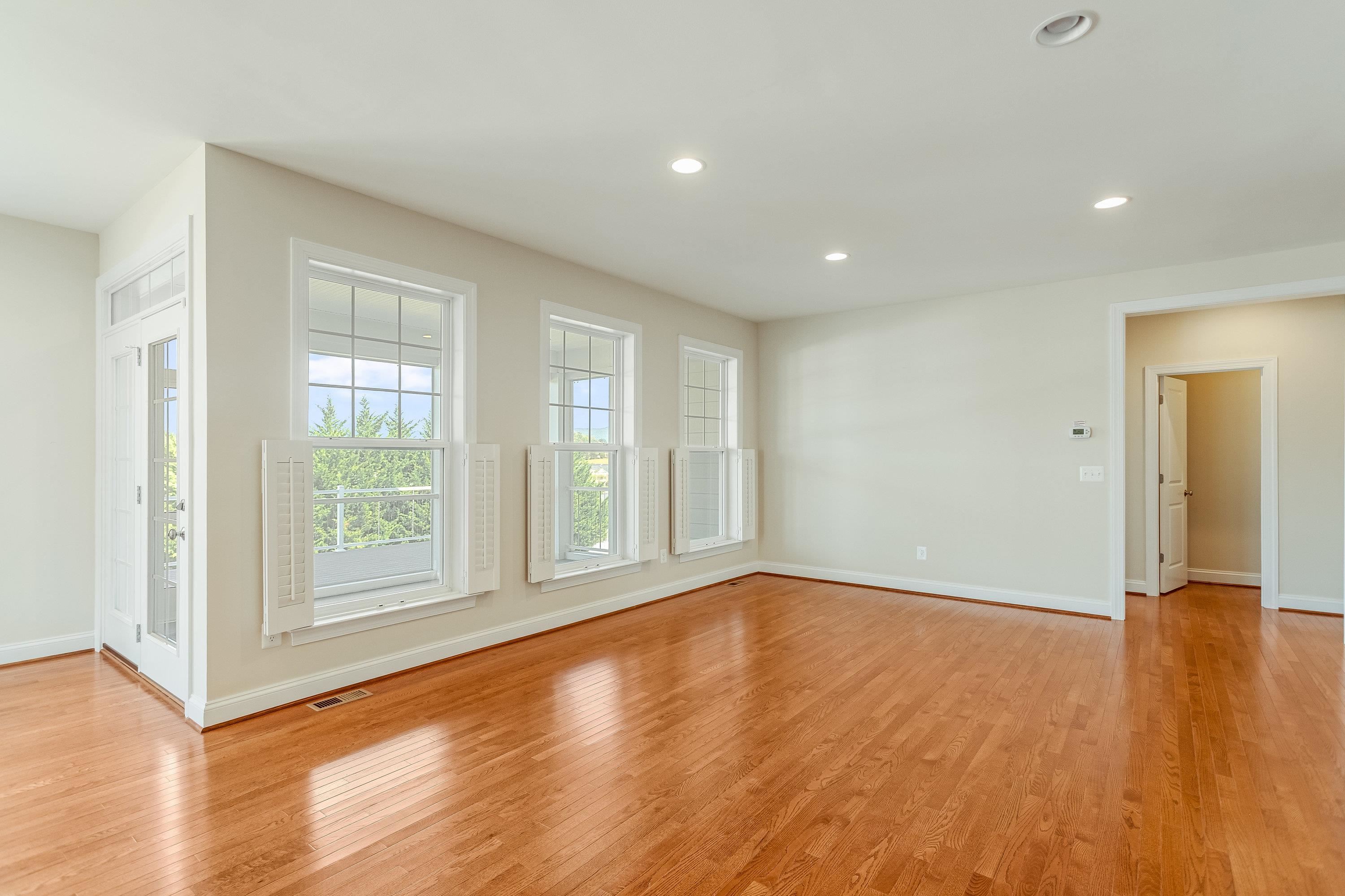 This very expansive living room space features hardwood floors, multiple large windows, elevated ceilings, recessed lighting, and plenty of space for gathering with friends and family.