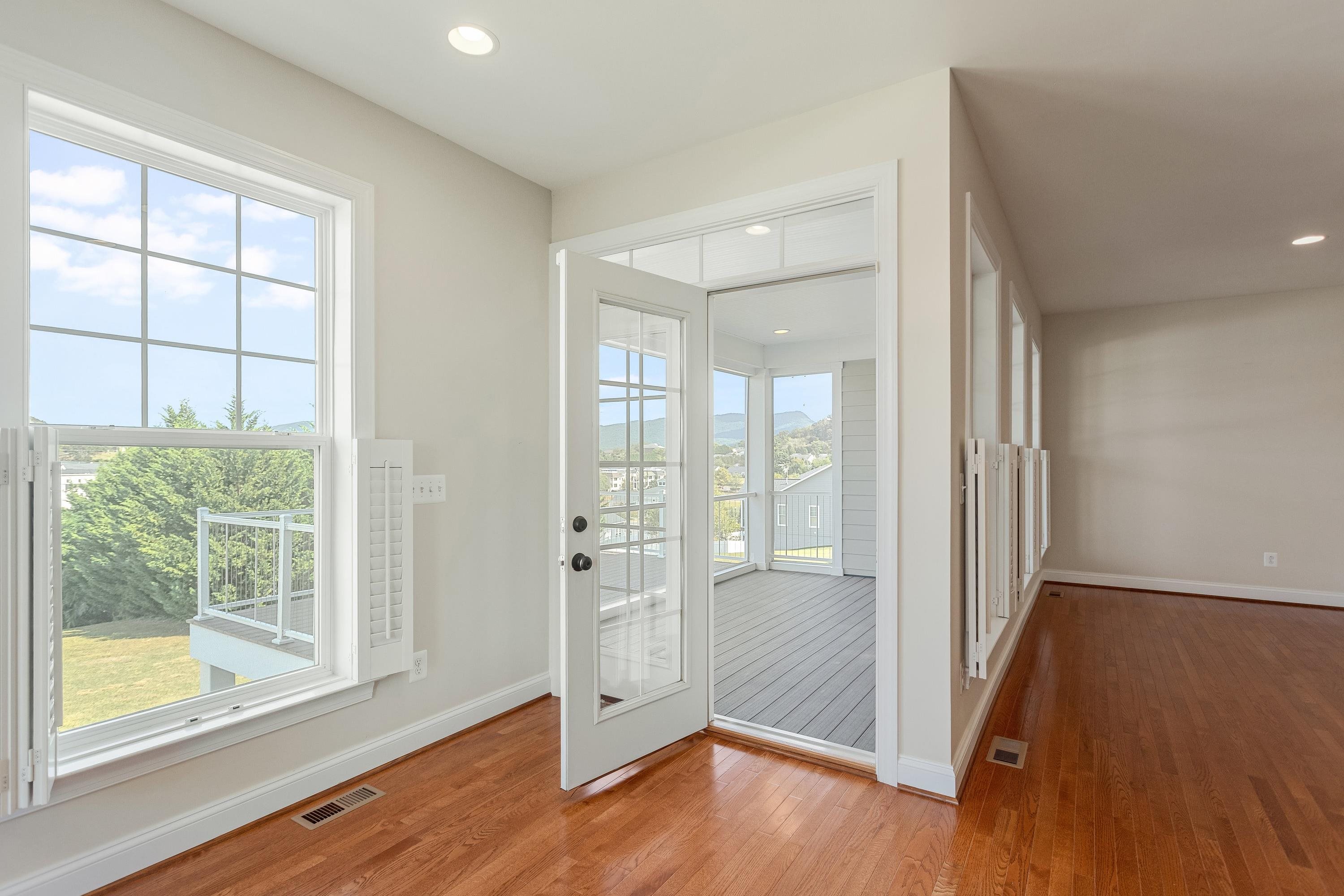 This very expansive living room space features hardwood floors, multiple large windows, elevated ceilings, recessed lighting, and plenty of space for gathering with friends and family.