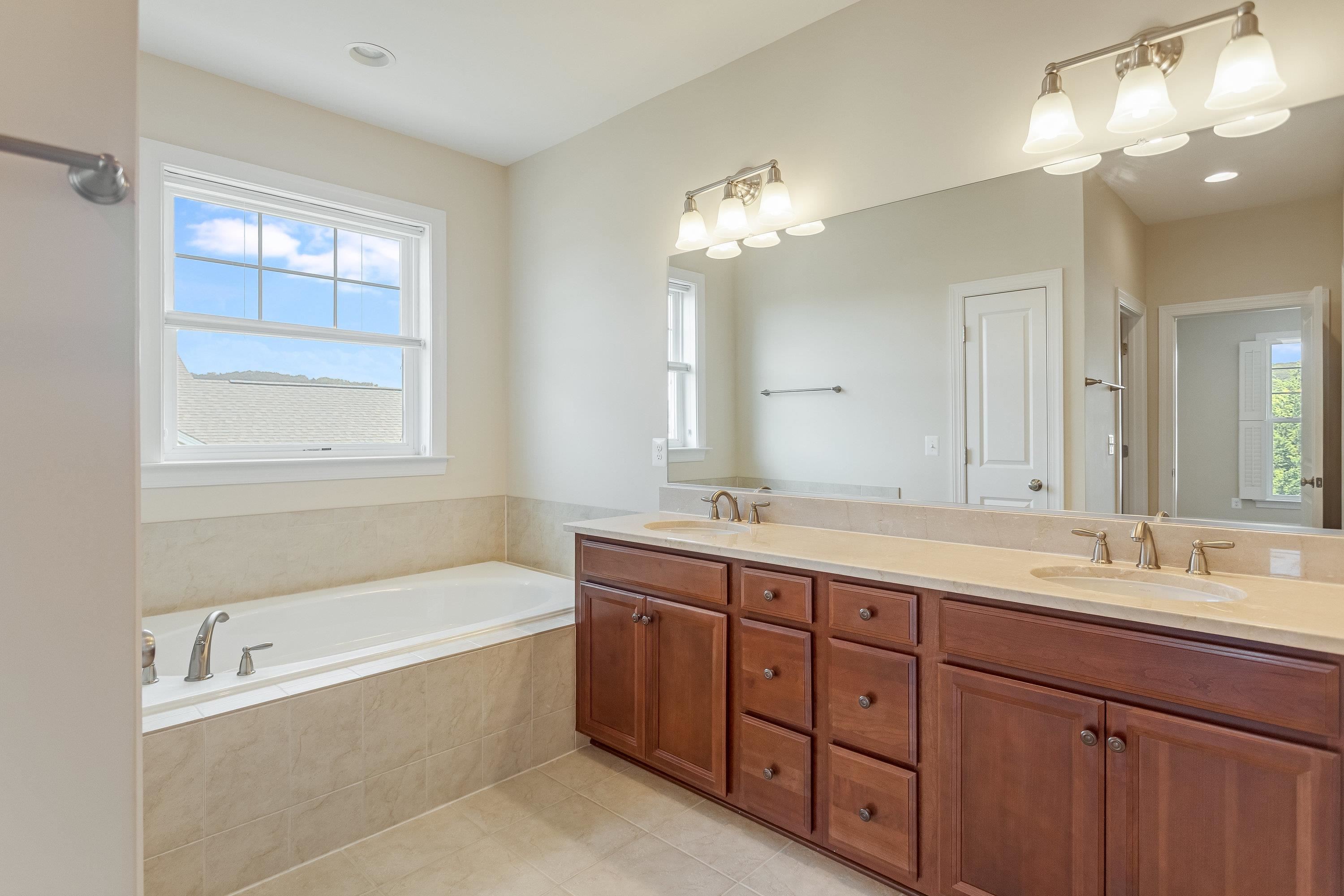 The primary bathroom offers tile flooring and dual vanities.  This bathroom features a whirlpool bathtub and seperate toilet/pedastal sink space.