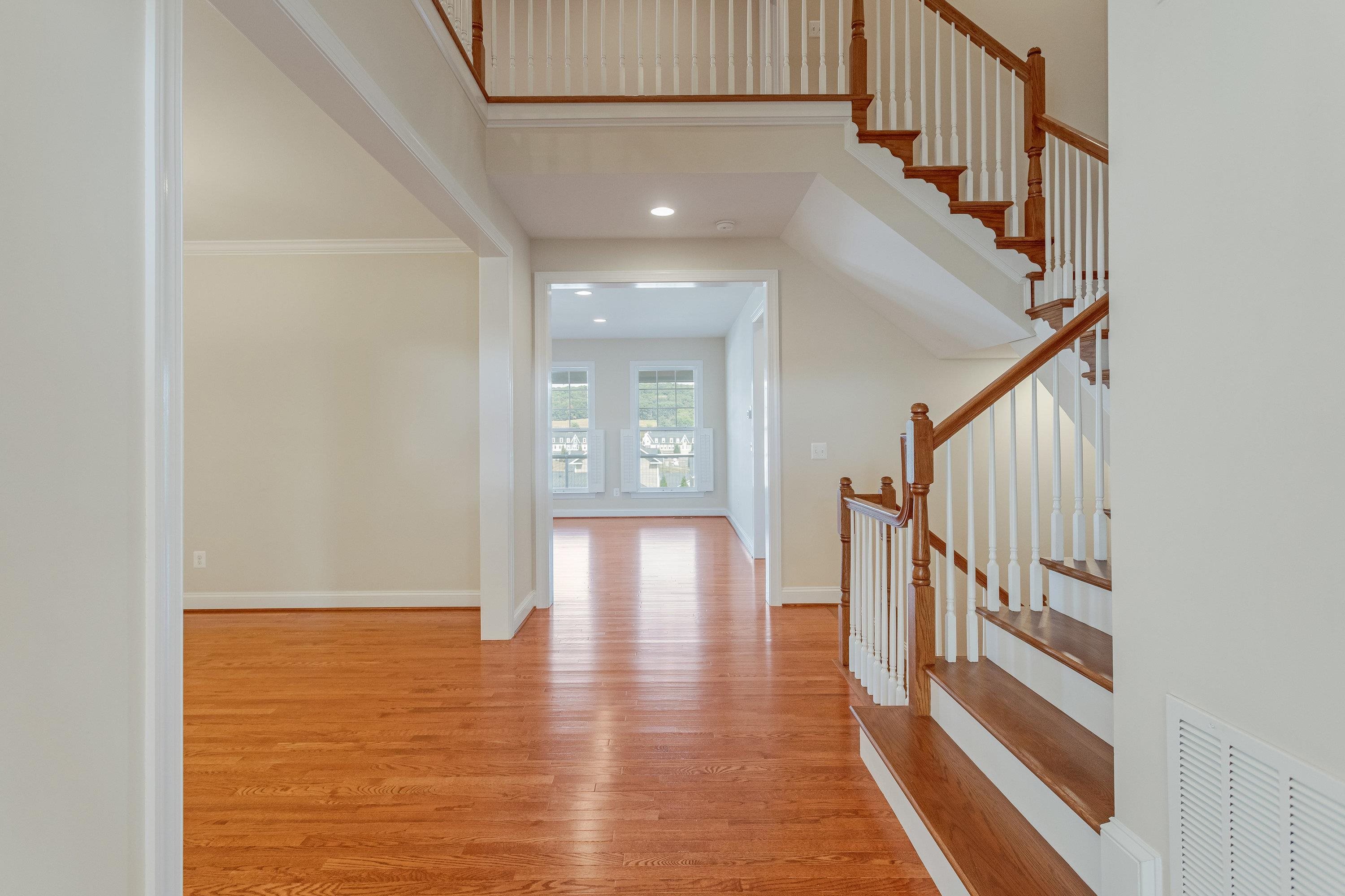 The foyer of the home offers hardwood flooring throughout and a spacious staircase with open railing.