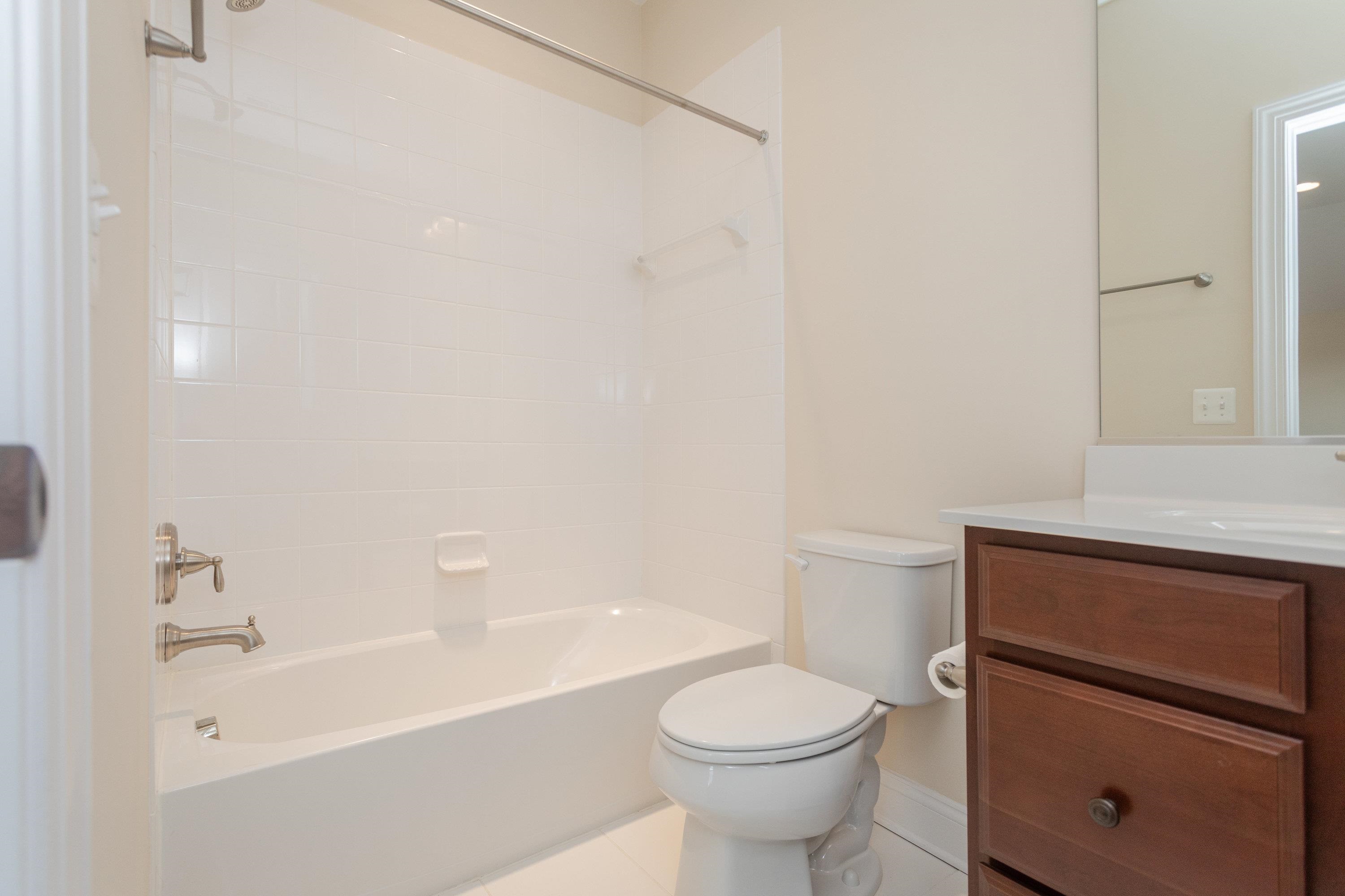 This full bathroom features a full bathtub/shower combination, tile flooring, and vanity with storage.