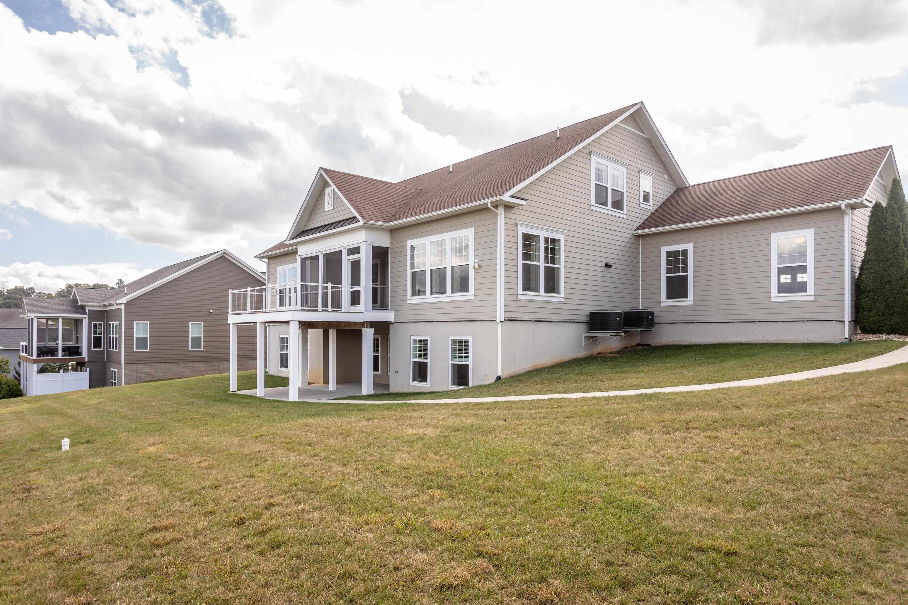 The rear view of the home highlights the spacious lot, screened-in porch, deck, covered patio, and much more!