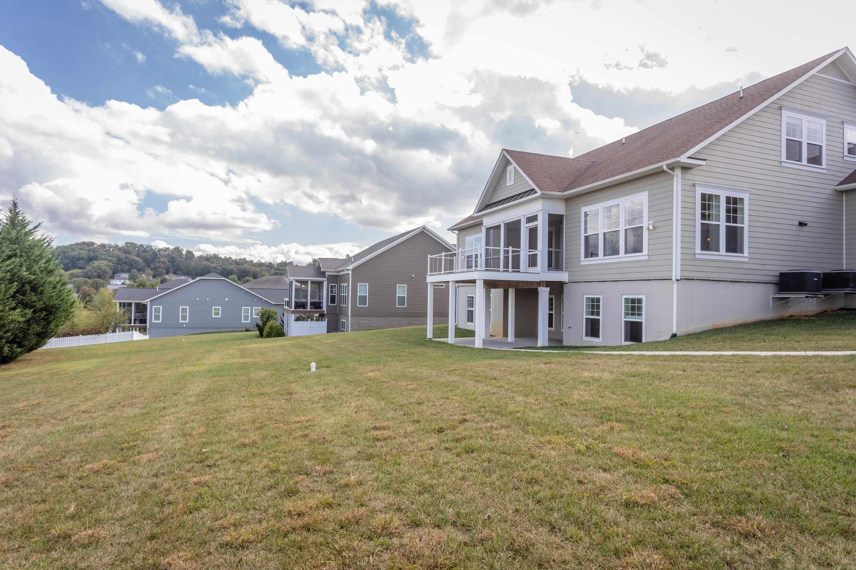The rear view of the home highlights the spacious lot, screened-in porch, deck, covered patio, and much more!