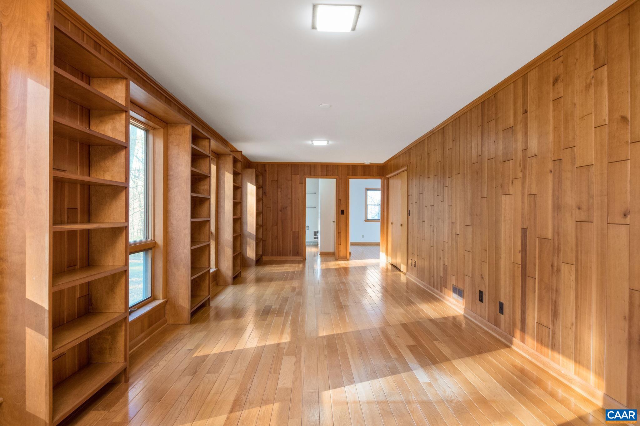 Unique artist made pocket door, righ wood-flooring and hand-cut cherry wood panelling.  Custom built-in floor to ceilign bookcases alternate with oversize floor to ceiling windows provide ample light and a beautiful view of front garden.