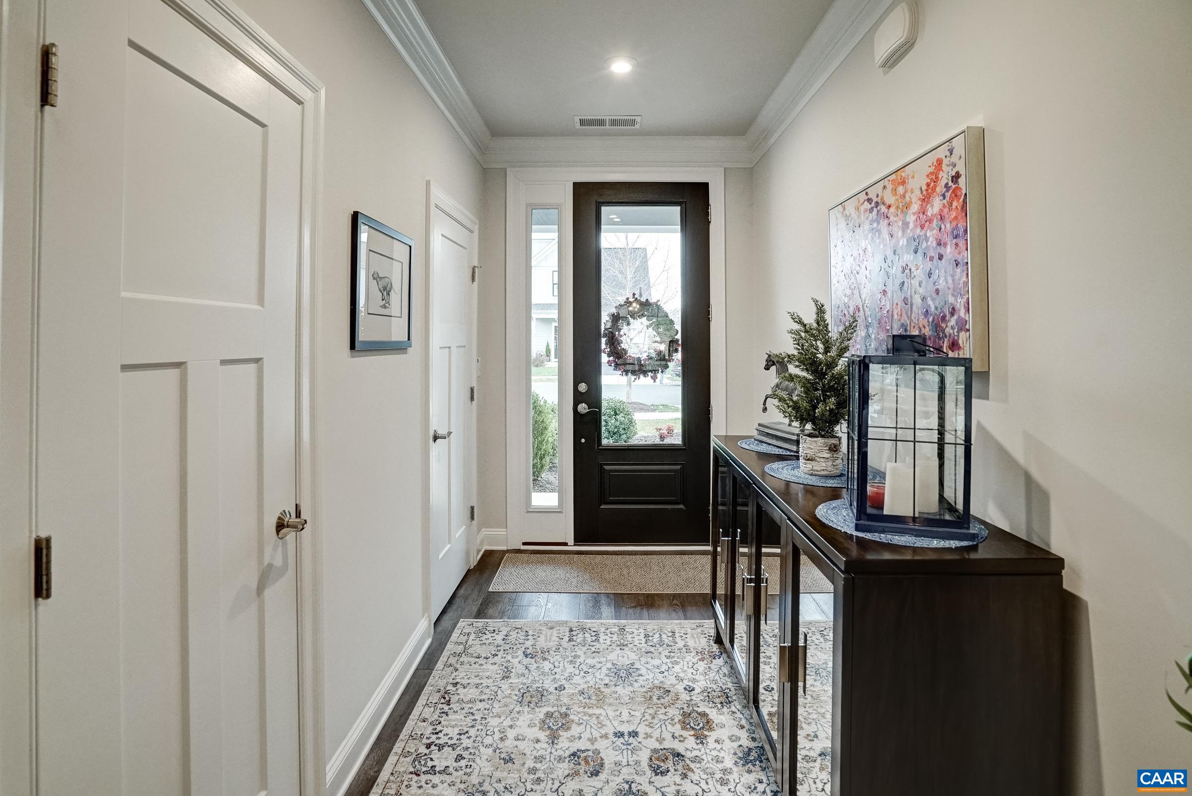 Light-filled foyer with luxury plank flooring and crown moulding. Light-filled foyer with luxury plank flooring and crown moulding.