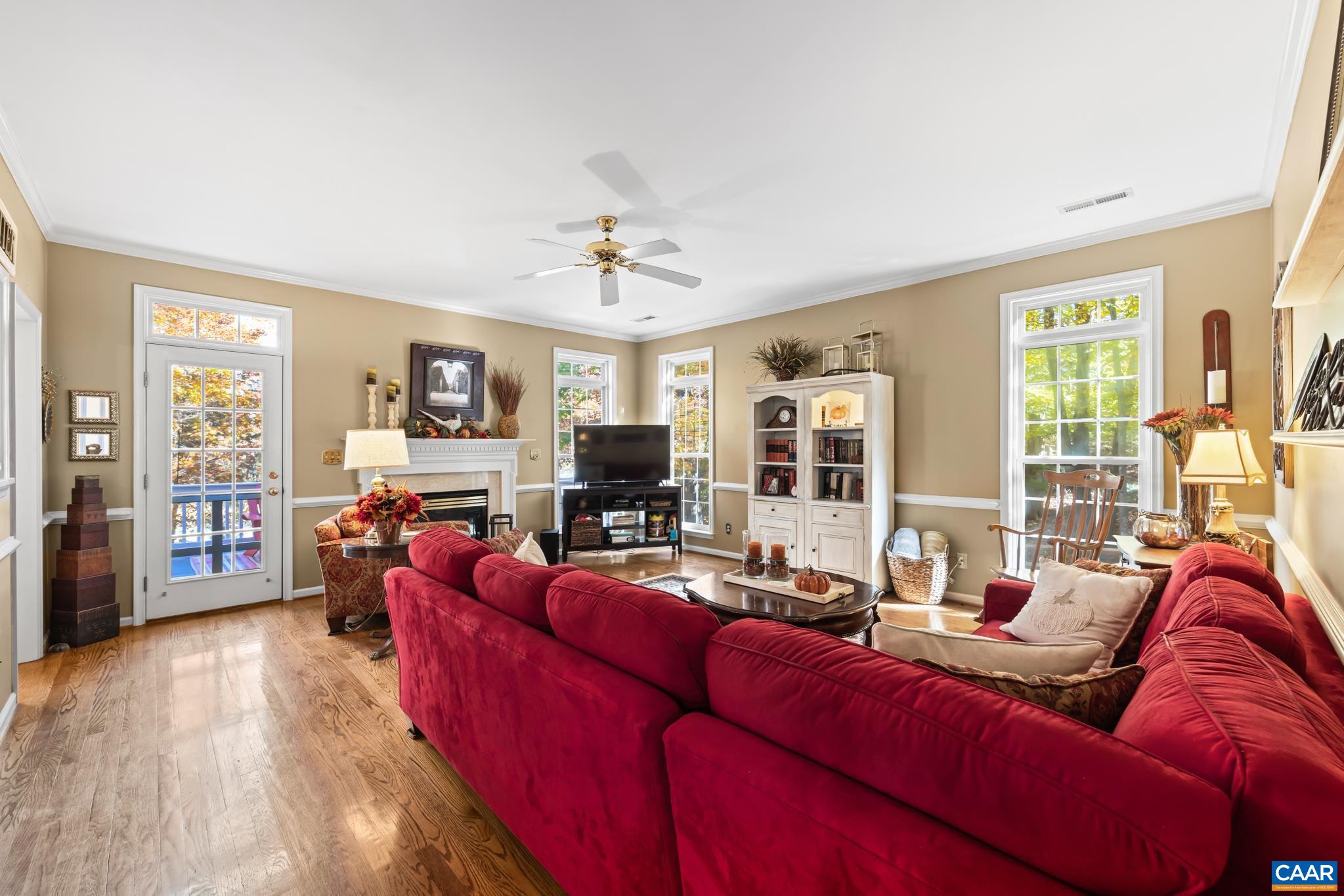Relax in this bright family room featuring beautiful hardwood floors, a cozy fireplace, and abundant natural light from the large windows and glass door leading to the rear deck. A ceiling fan ensures comfort in this inviting area. Relax in this bright family room featuring beautiful hardwood floors, a cozy fireplace, and abundant natural light from the large windows and glass door leading to the rear deck. A ceiling fan ensures comfort in this inviting area.