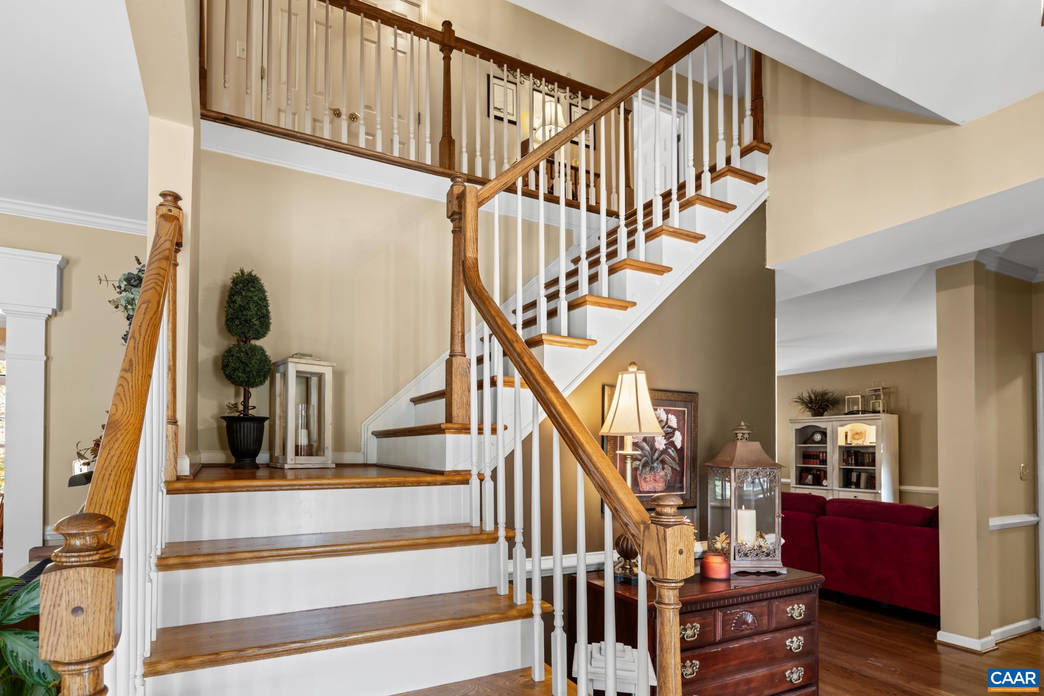 A cathedral ceiling is accented by an elegant staircase with white risers and a natural wood railing. Each comfortable living space is circularly accessed and promises classic warmth and charm. A cathedral ceiling is accented by an elegant staircase with white risers and a natural wood railing. Each comfortable living space is circularly accessed and promises classic warmth and charm.