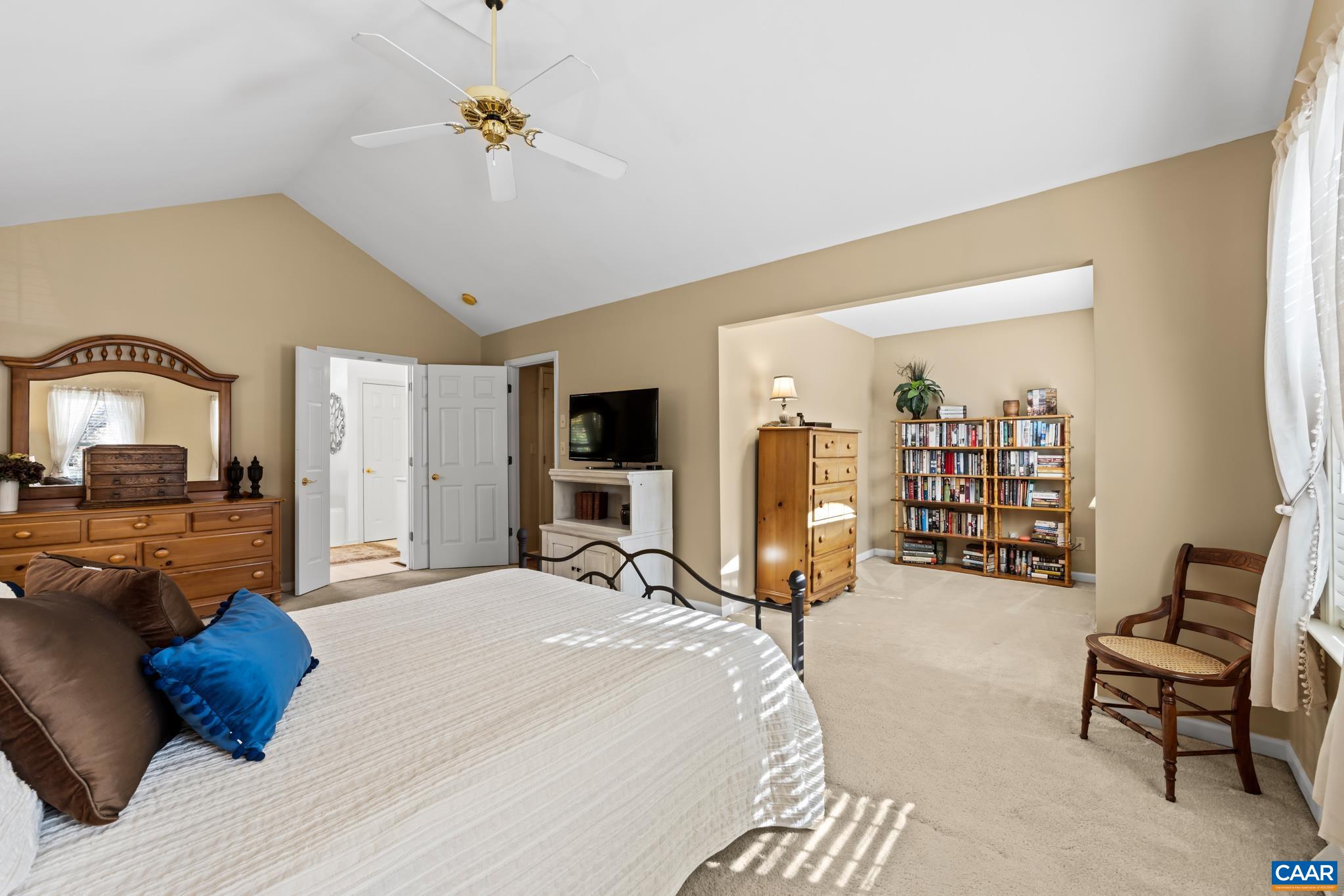 Retreat to the spacious primary bedroom featuring a vaulted ceiling with a fan and a separate sitting area perfect for a reading nook or home office. Enjoy the walk-in closet access and ensuite bath from this tranquil space. Retreat to the spacious primary bedroom featuring a vaulted ceiling with a fan and a separate sitting area perfect for a reading nook or home office. Enjoy the walk-in closet access and ensuite bath from this tranquil space.