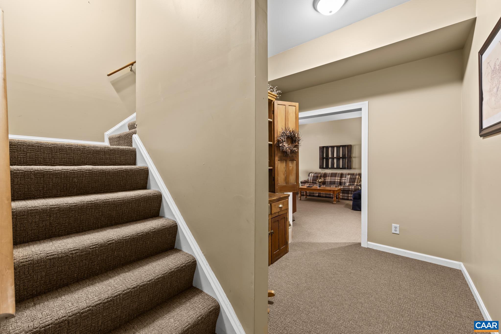 Descend into the finished basement on a plush, carpeted staircase. This lower level offers a bright hallway leading to a versatile recreation room with warm carpet, a cozy sitting area, and ample space for relaxation or recreation. Descend into the finished basement on a plush, carpeted staircase. This lower level offers a bright hallway leading to a versatile recreation room with warm carpet, a cozy sitting area, and ample space for relaxation or recreation.