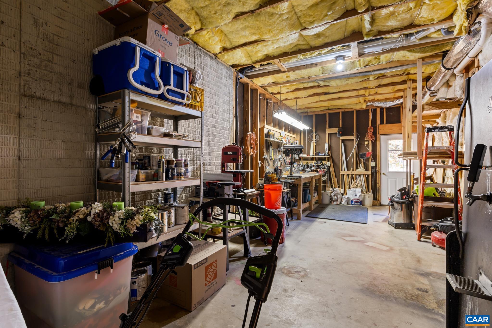 This spacious workshop or storage area offers endless possibilities for DIY projects and organization. With exposed framing, a concrete floor, ample shelving, and workbenches, it's a dedicated area for tools and hobbies. Unfinished part of basement. This spacious workshop or storage area offers endless possibilities for DIY projects and organization. With exposed framing, a concrete floor, ample shelving, and workbenches, it's a dedicated area for tools and hobbies. Unfinished part of basement.