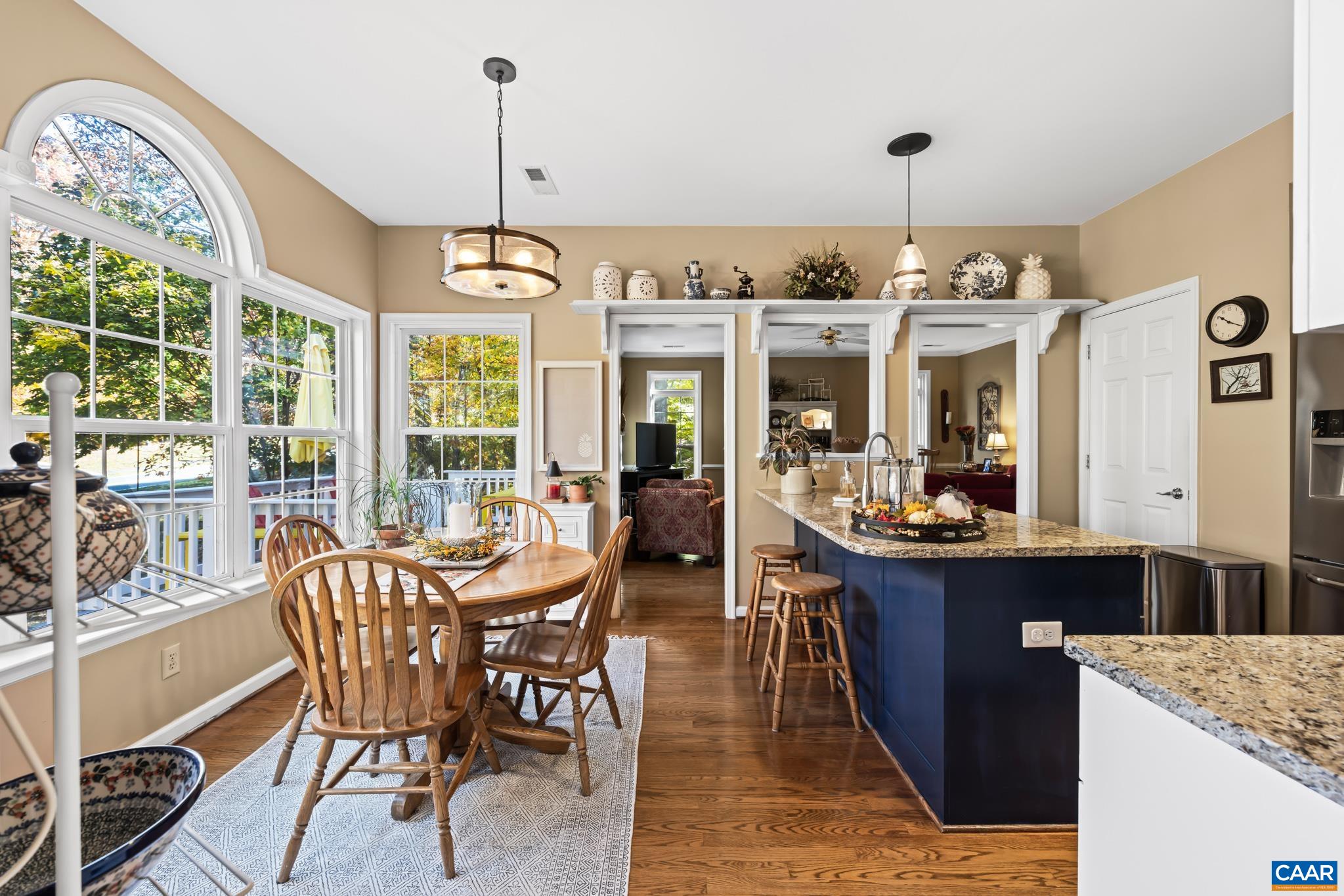Enjoy casual dining in this bright kitchen with a large window bay, providing abundant natural light and beautiful wooded views. Features include a granite-topped island with seating and lower dark blue cabinets to accent the surrounding white cabinetry. Enjoy casual dining in this bright kitchen with a large window bay, providing abundant natural light and beautiful wooded views. Features include a granite-topped island with seating and lower dark blue cabinets to accent the surrounding white cabinetry.
