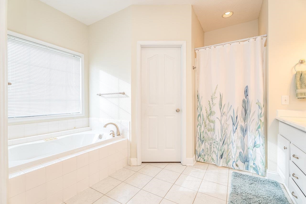 Features: Dual vanities, tile floors, a shower and whirlpool tub, all complemented by ample lighting.