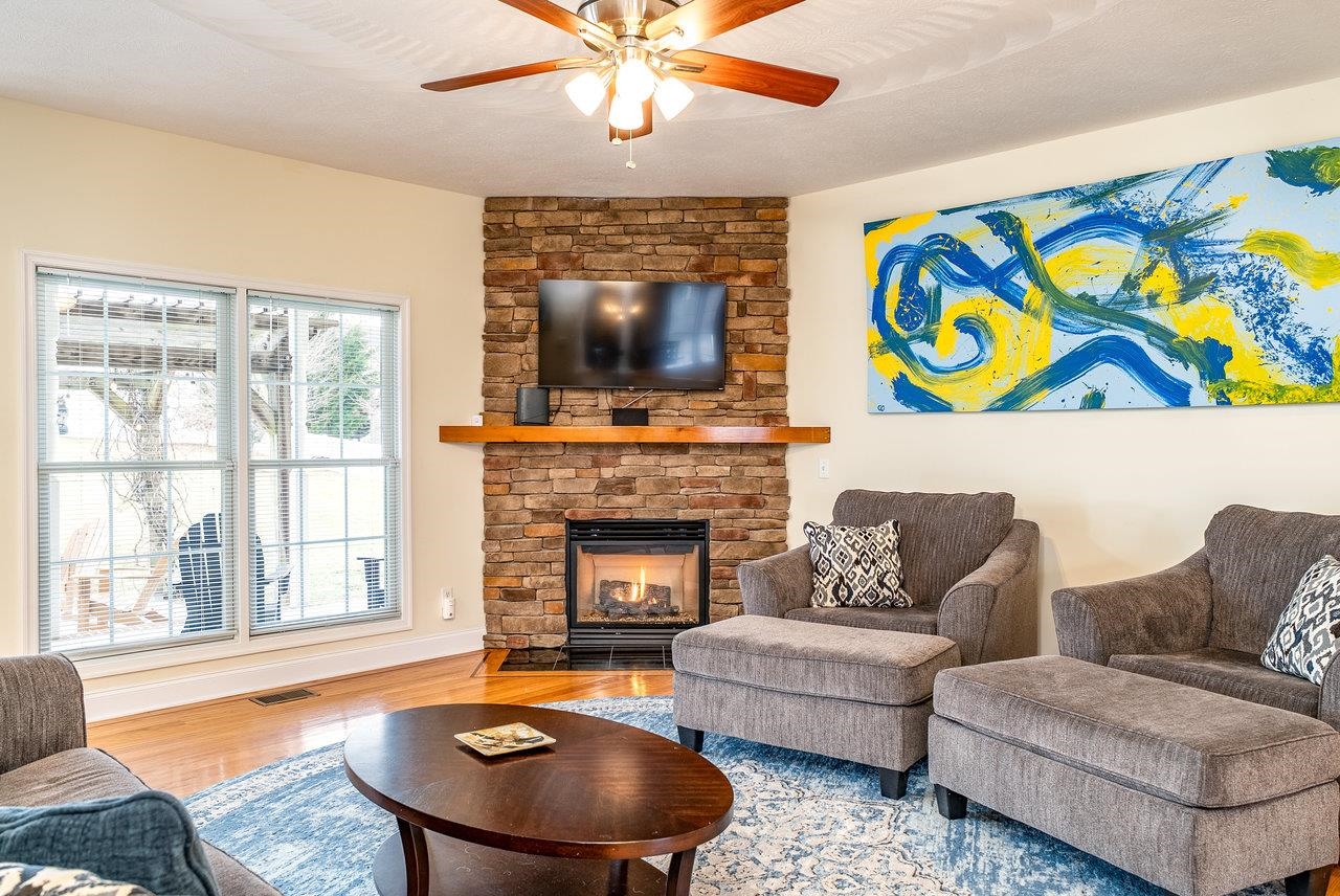 Features: Wood floors with elegant inlay, a stone gas fireplace, and a ceiling fan.