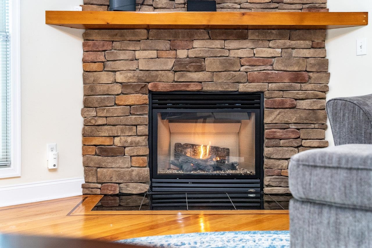 Features: Gas fireplace featuring a stunning stone surround and a handcrafted wood mantel, creating a warm and inviting focal point.