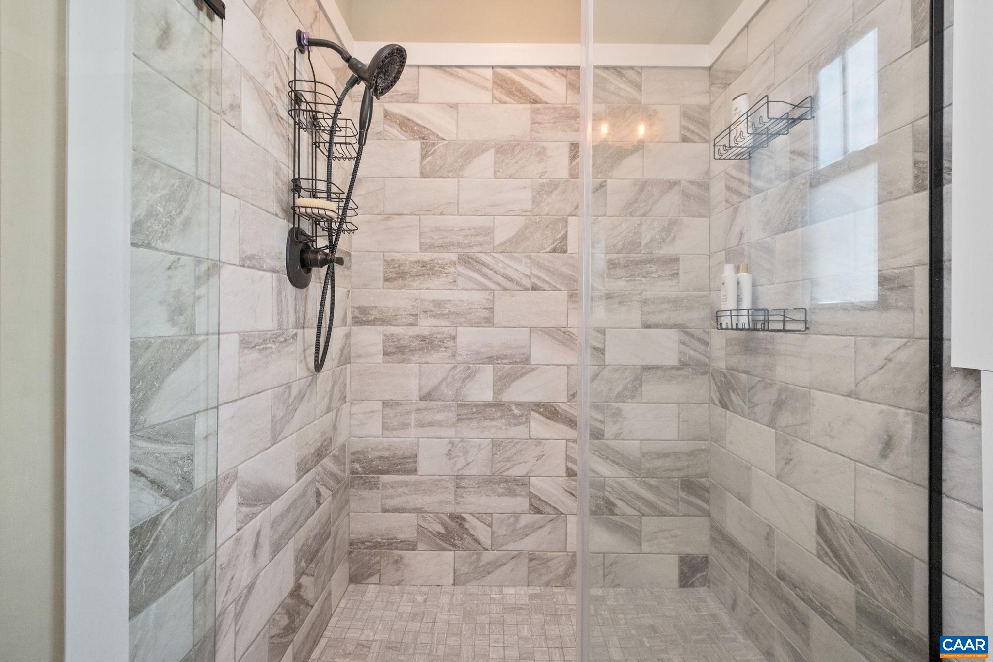 Tiled shower features glass doors.