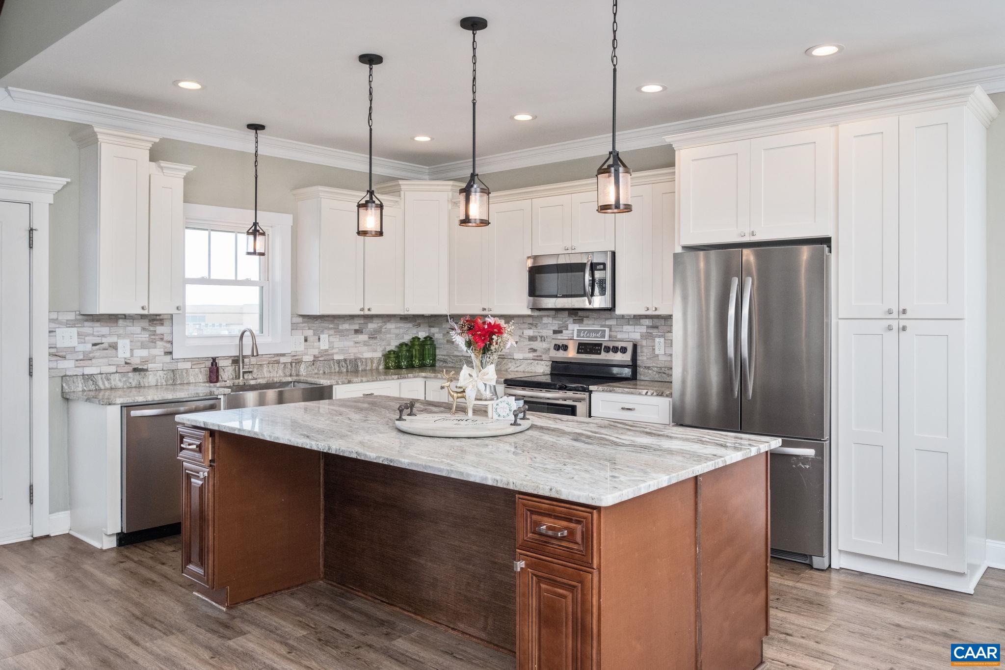 The main level features a large kitchen, with island that includes electrical outlets, seating area, plenty of cabinetry, and granite countertops.