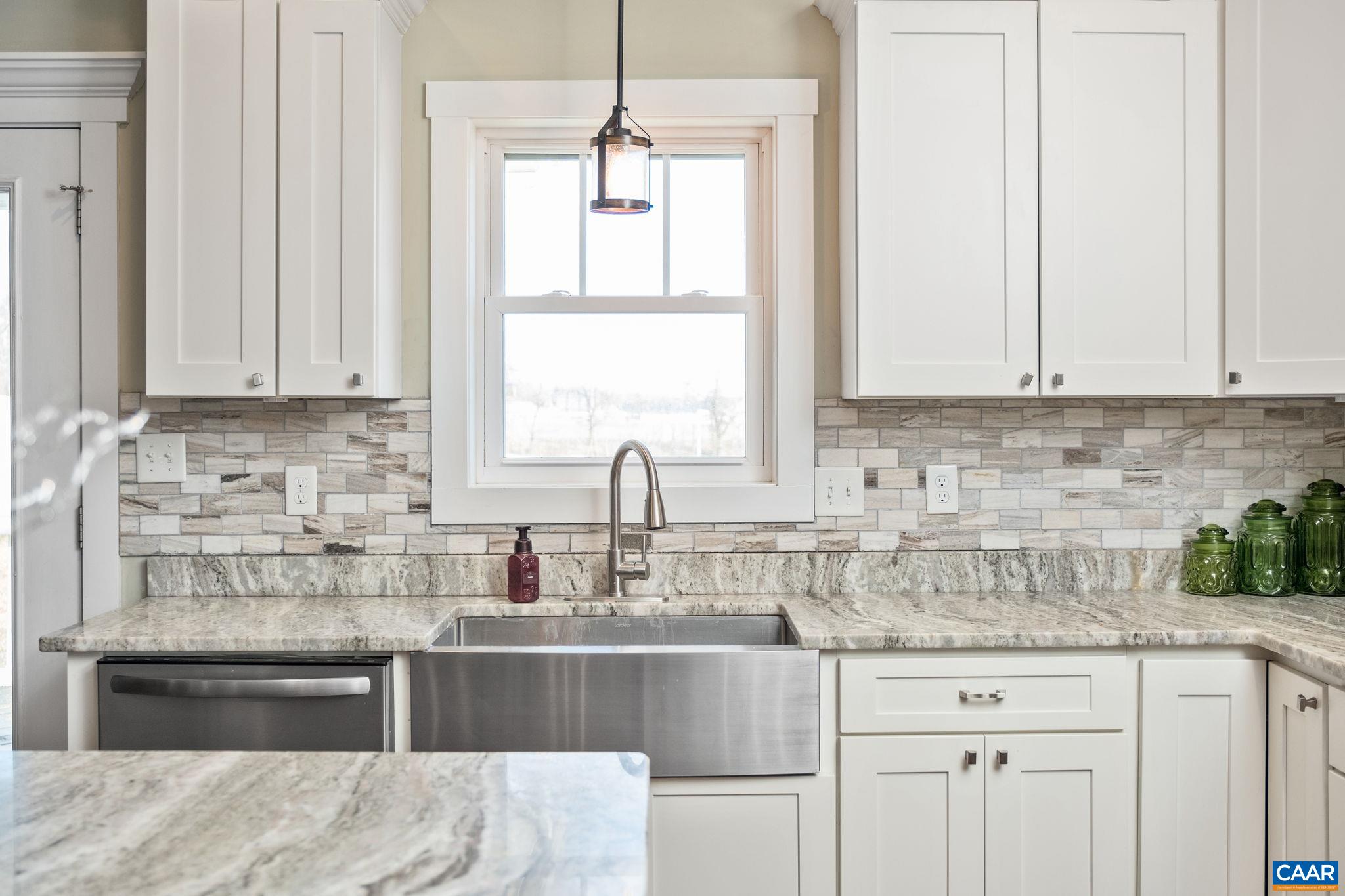 The kitchen also features a tile backsplash, farmhouse sink, and stainless steel appliances.