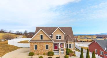 Exterior of the home features stone, newer roof, concrete driveway, and fully fenced backyard.