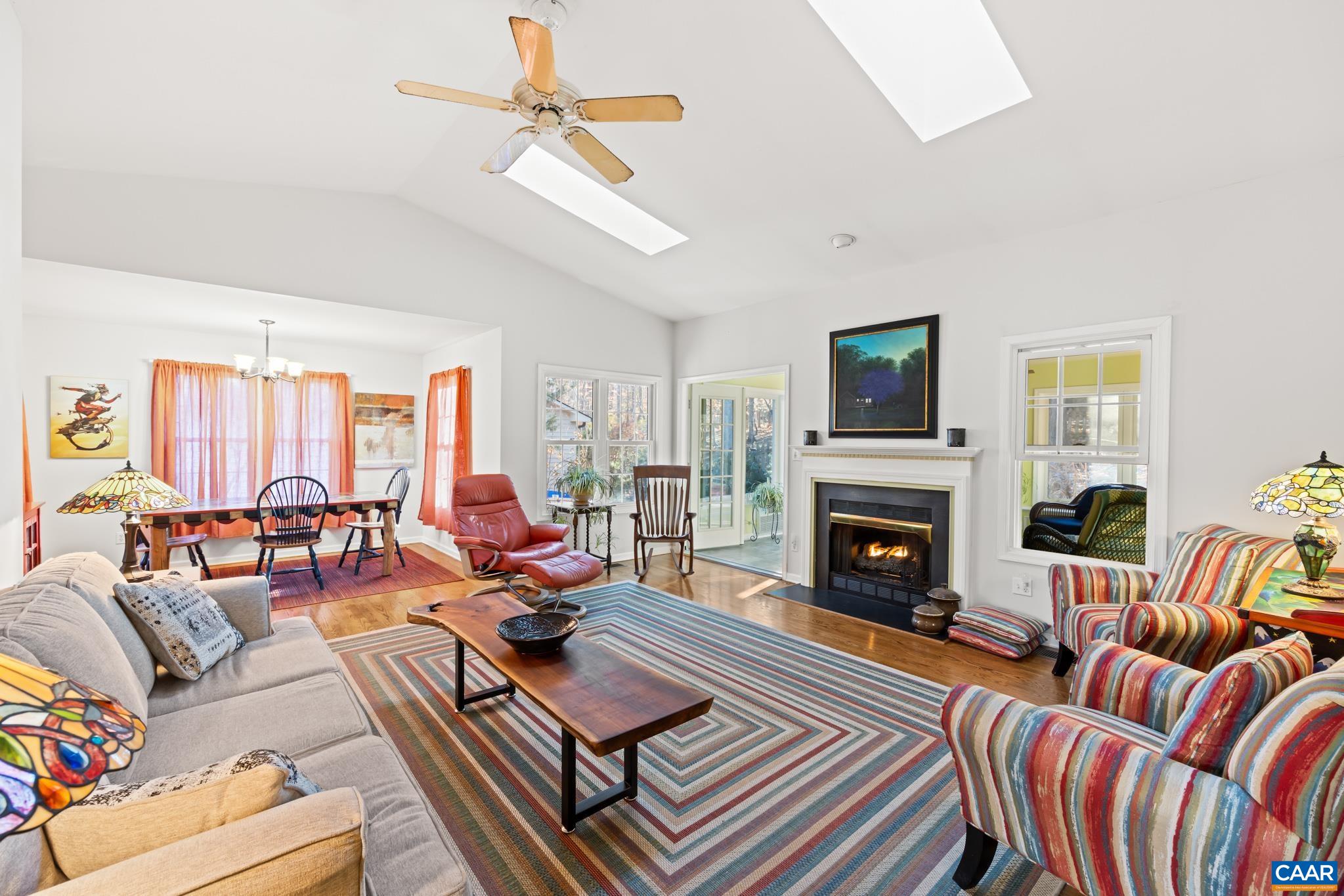 Spacious living room with vaulted ceilings, hardwood floors, and a gas fireplace seamlessly connected to the open floor plan-perfect for everyday living and entertaining.