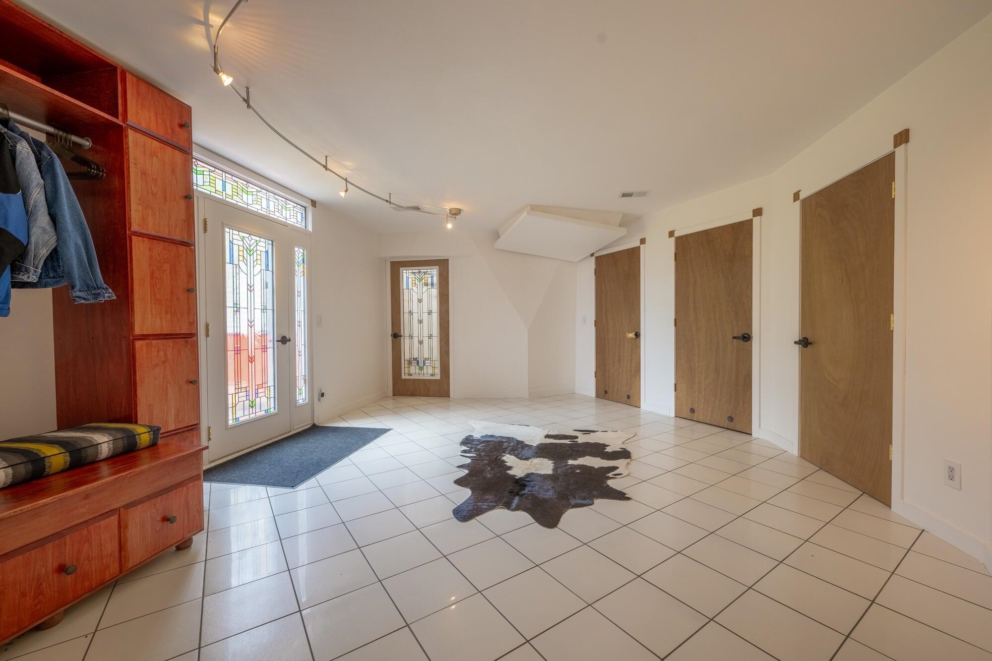 Enter into the Foyer with tile floors, Clothing rack, doors to utility spaces.