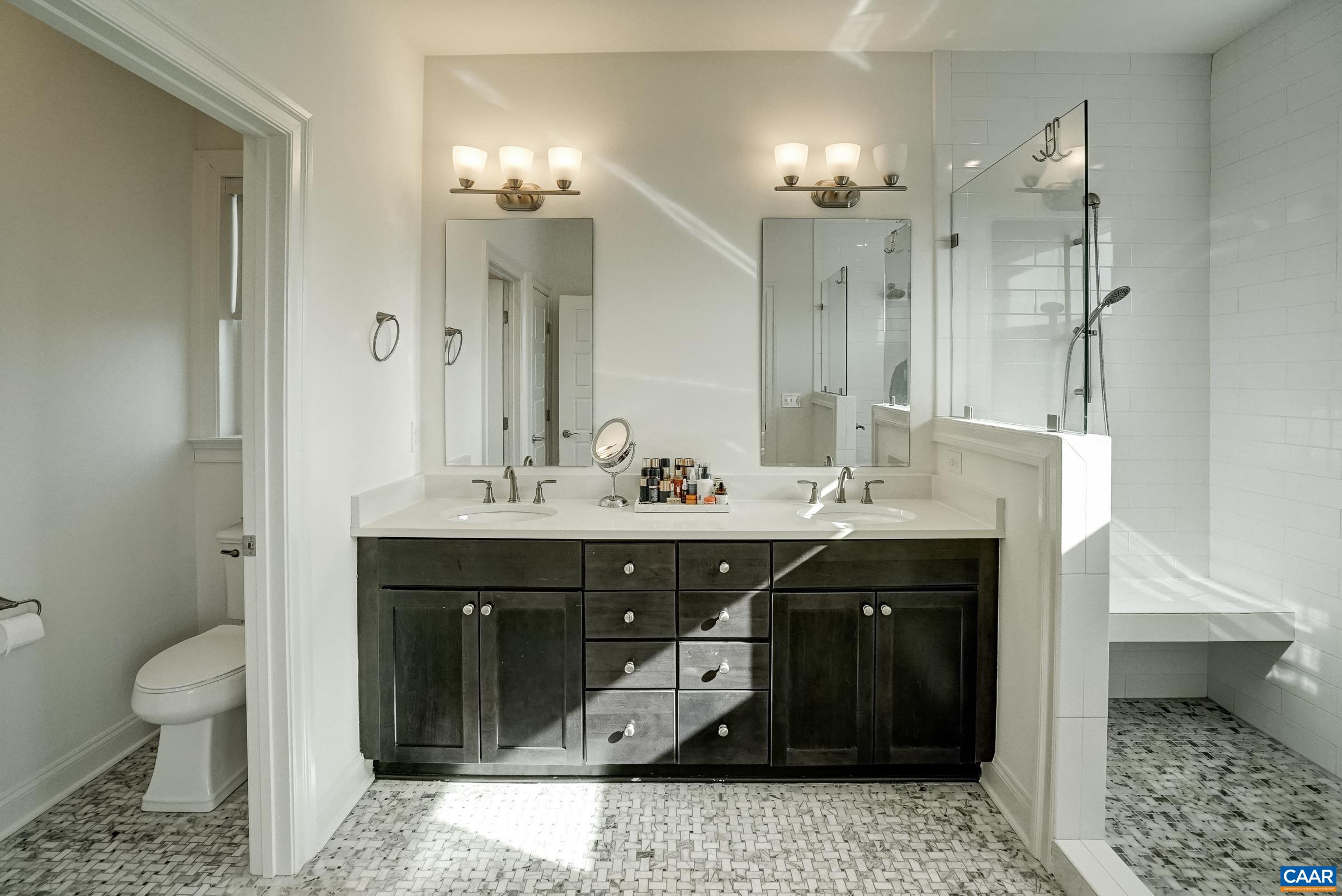Ensuite bathroom features frameless glass walk-in shower, double sink vanity, new lighting and mirrors.