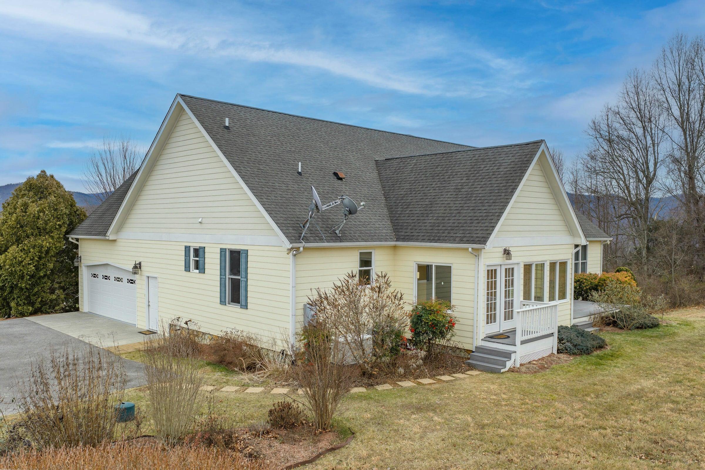 View behind the house shows access to the garage, and steps to the sun room.