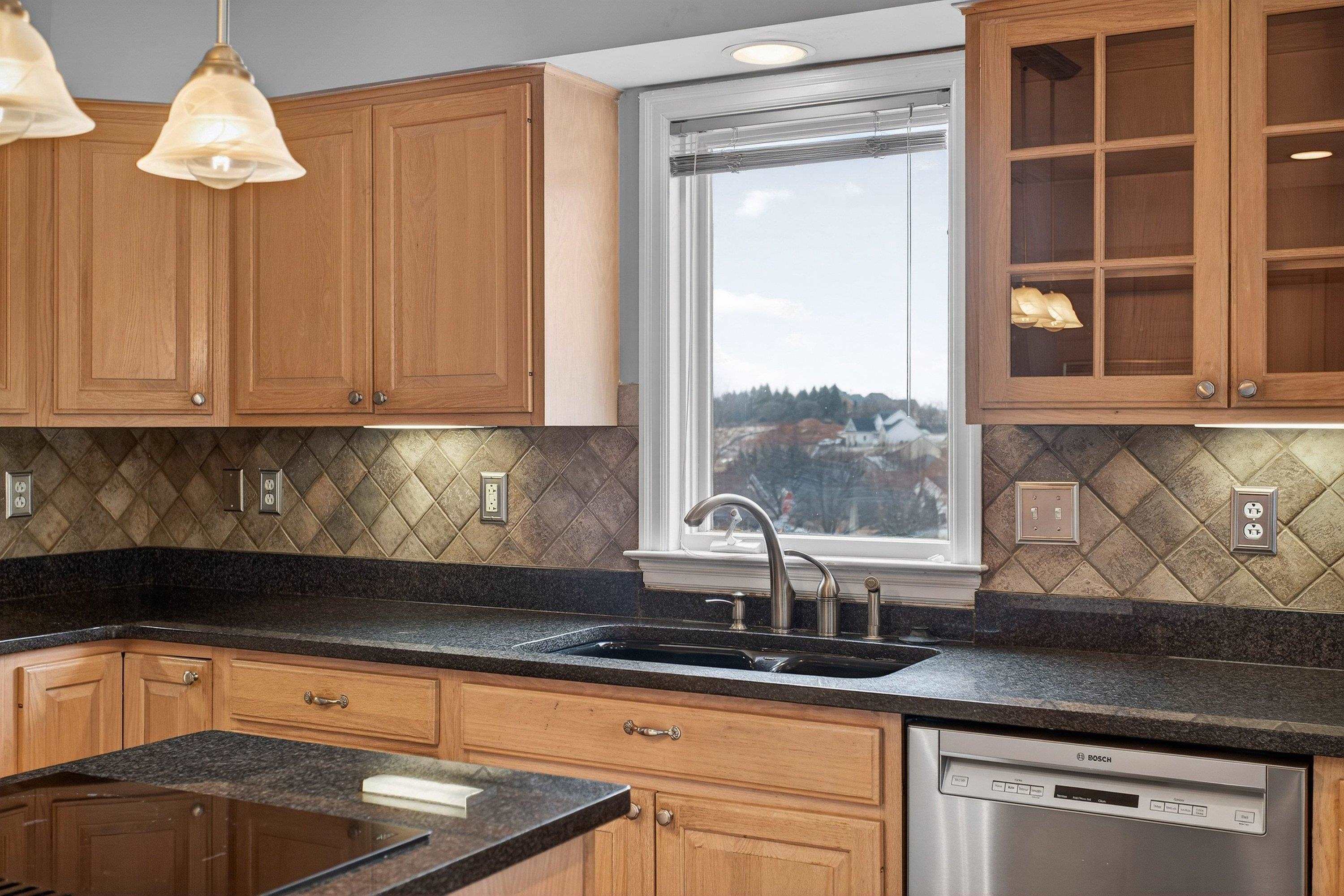 The large kitchen is located near the rear of the home and features ceramic tile flooring, granite counter-tops, wooden cabinetry, recessed lighting, and stainless steel appliances.