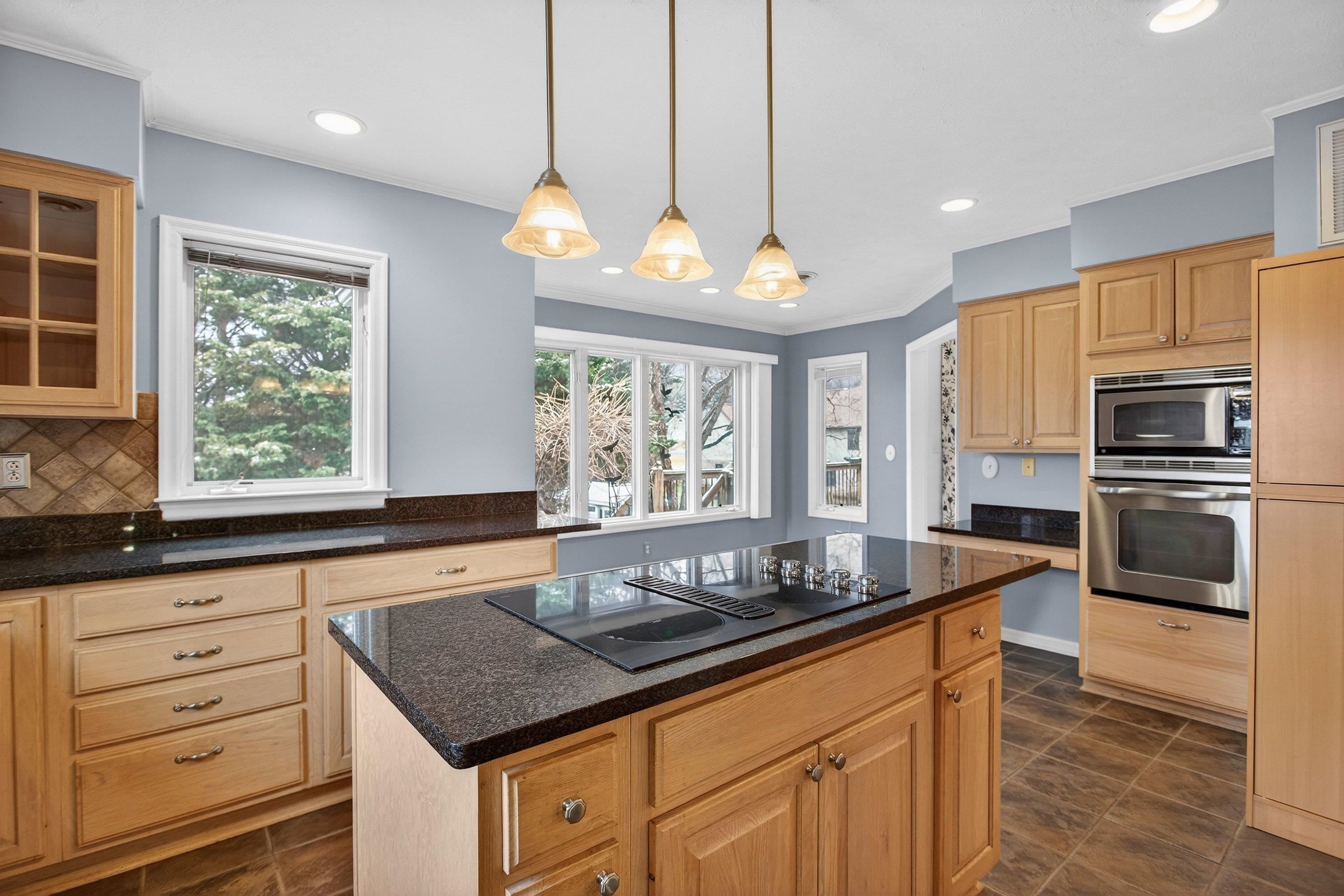 The large kitchen is located near the rear of the home and features ceramic tile flooring, granite counter-tops, wooden cabinetry, recessed lighting, and stainless steel appliances.