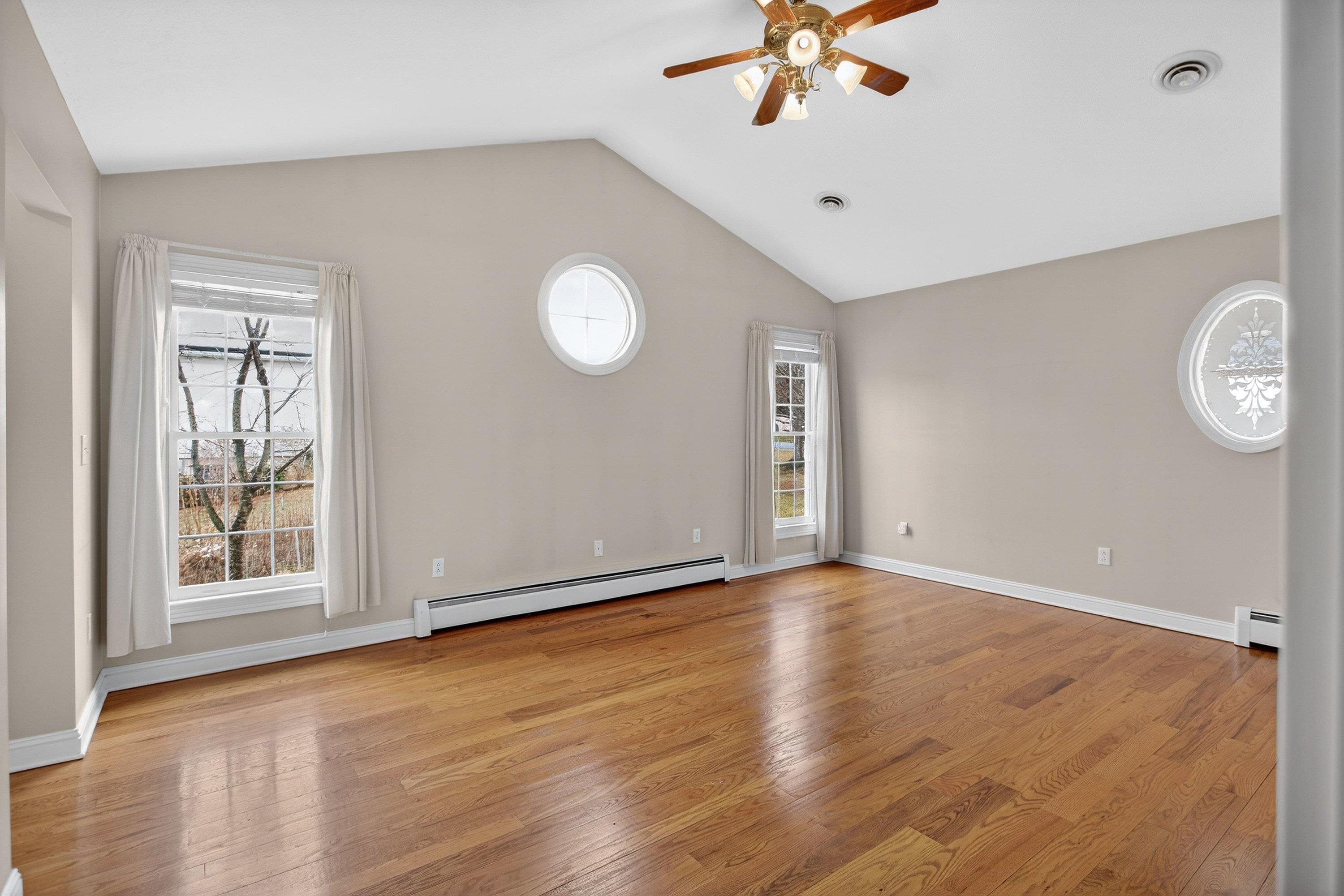 The primary bedroom offers vaulted ceilings and hardwood flooring throughout.  This space also features a ceiling fan, large windows, spacious walk-in closet space, and attached full bathroom.