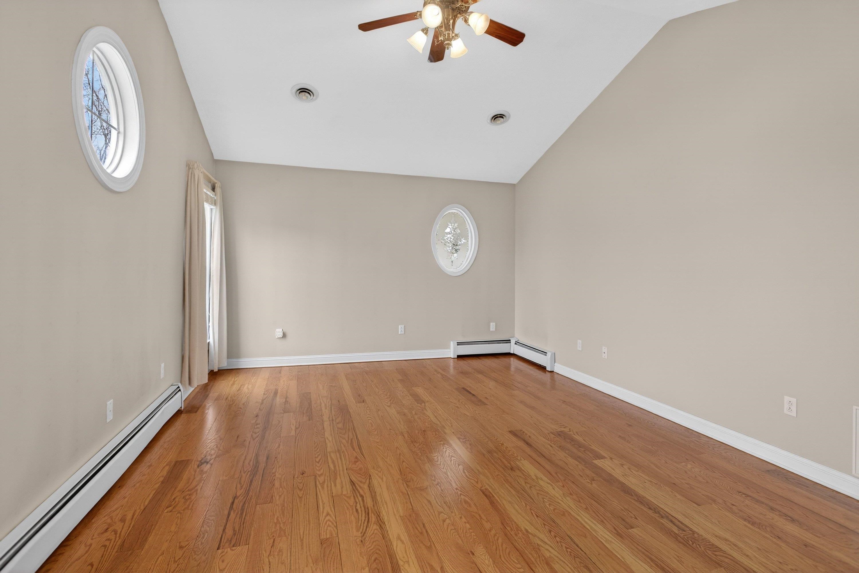 The primary bedroom offers vaulted ceilings and hardwood flooring throughout.  This space also features a ceiling fan, large windows, spacious walk-in closet space, and attached full bathroom.