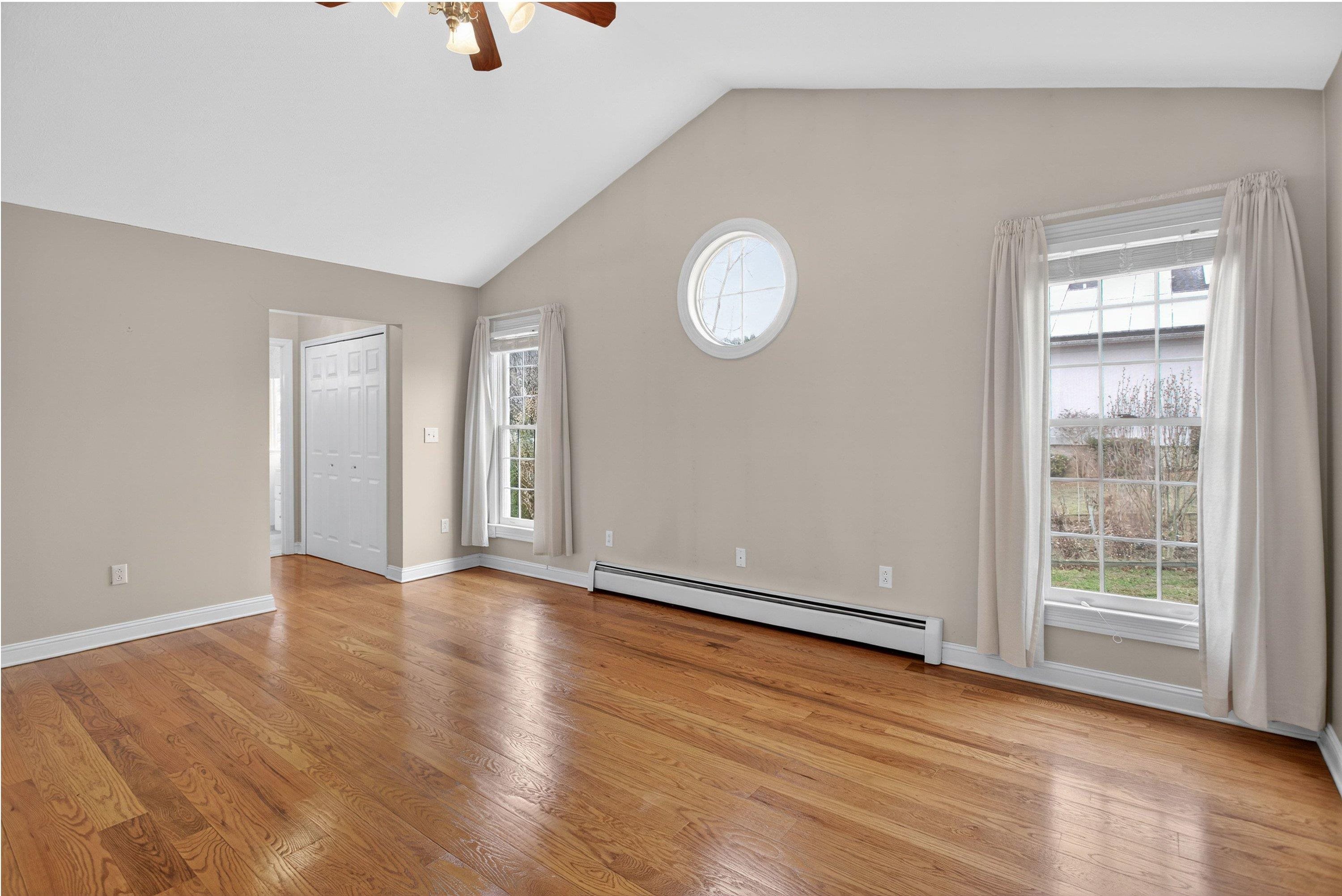 The primary bedroom offers vaulted ceilings and hardwood flooring throughout.  This space also features a ceiling fan, large windows, spacious walk-in closet space, and attached full bathroom.
