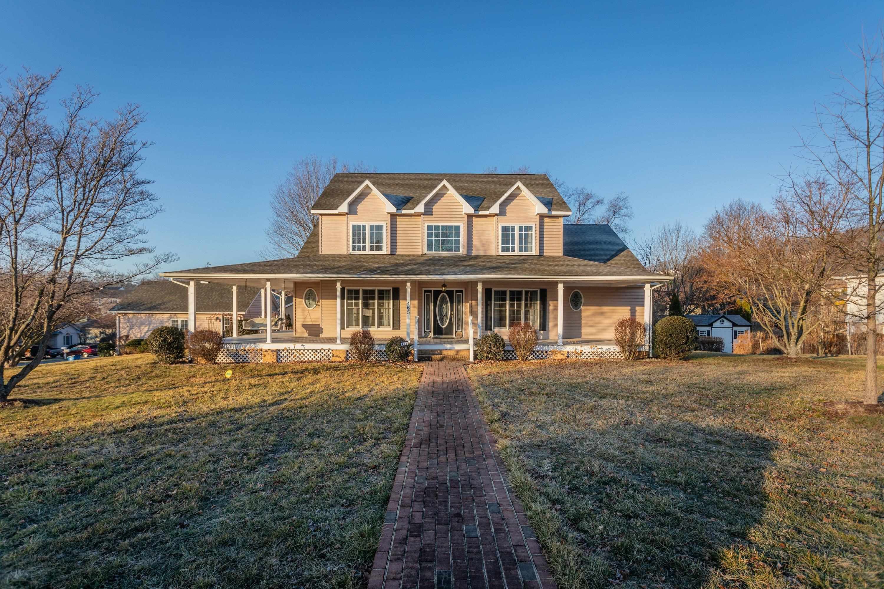 The front view of the home highlights the large wrap-around porch of the home, detached garage, large level yard of the home, and much more!