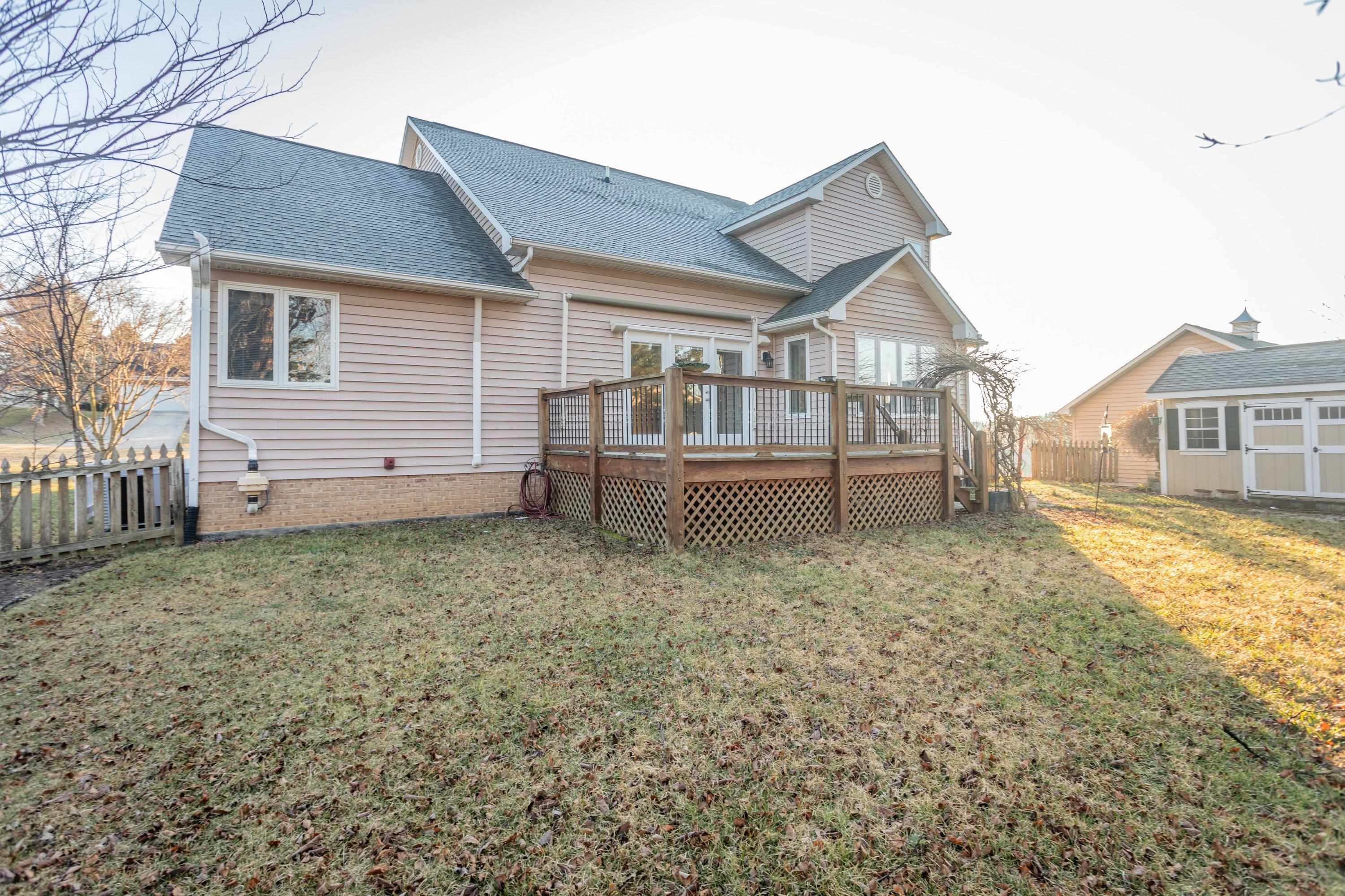 The rear of the home highlights the spacious wooden deck off the rear of the home.  These photos capture the large, level backyard area, landscaping, and storage building.