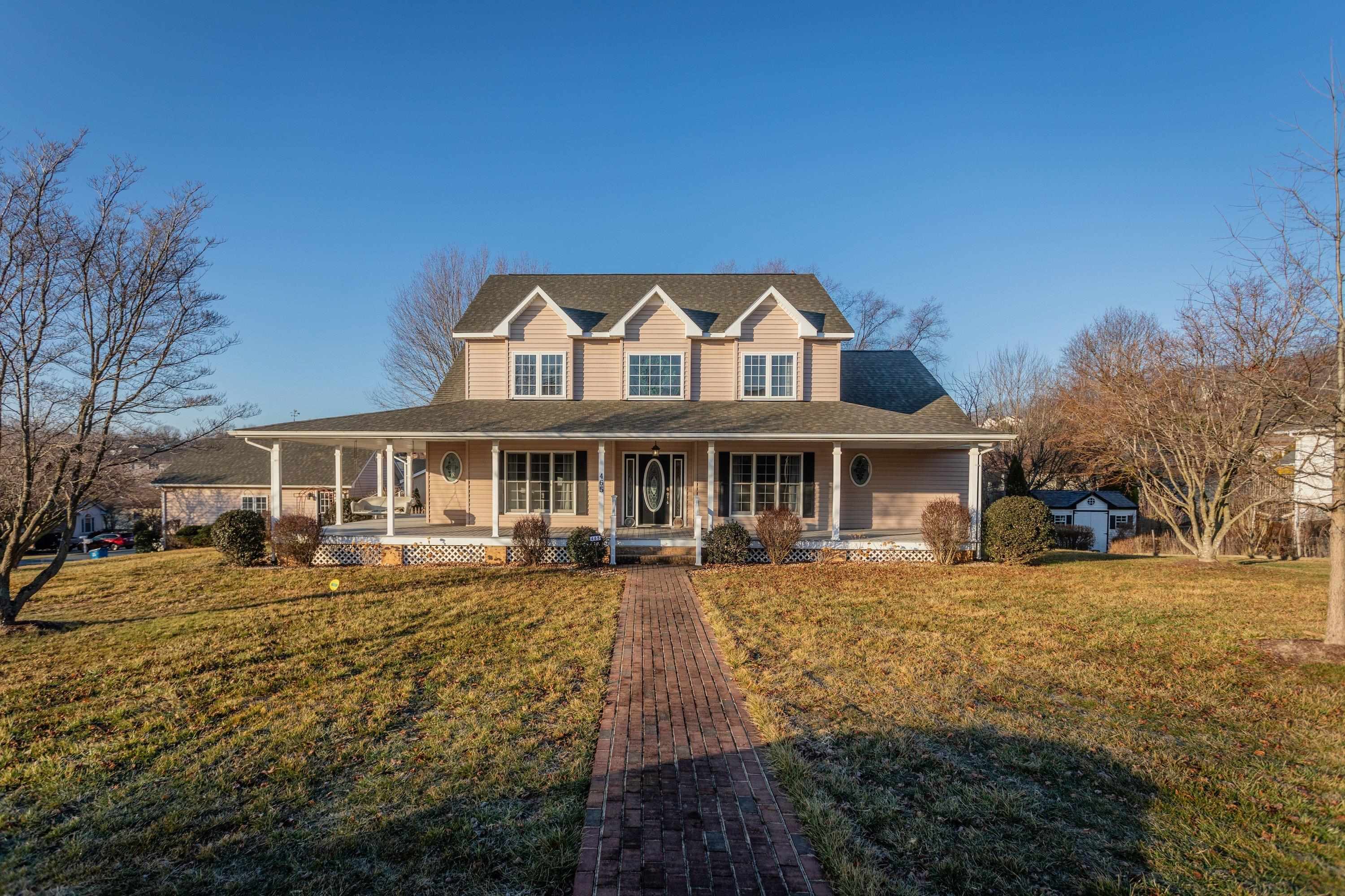 The front view of the home highlights the large wrap-around porch of the home, detached garage, large level yard of the home, and much more!
