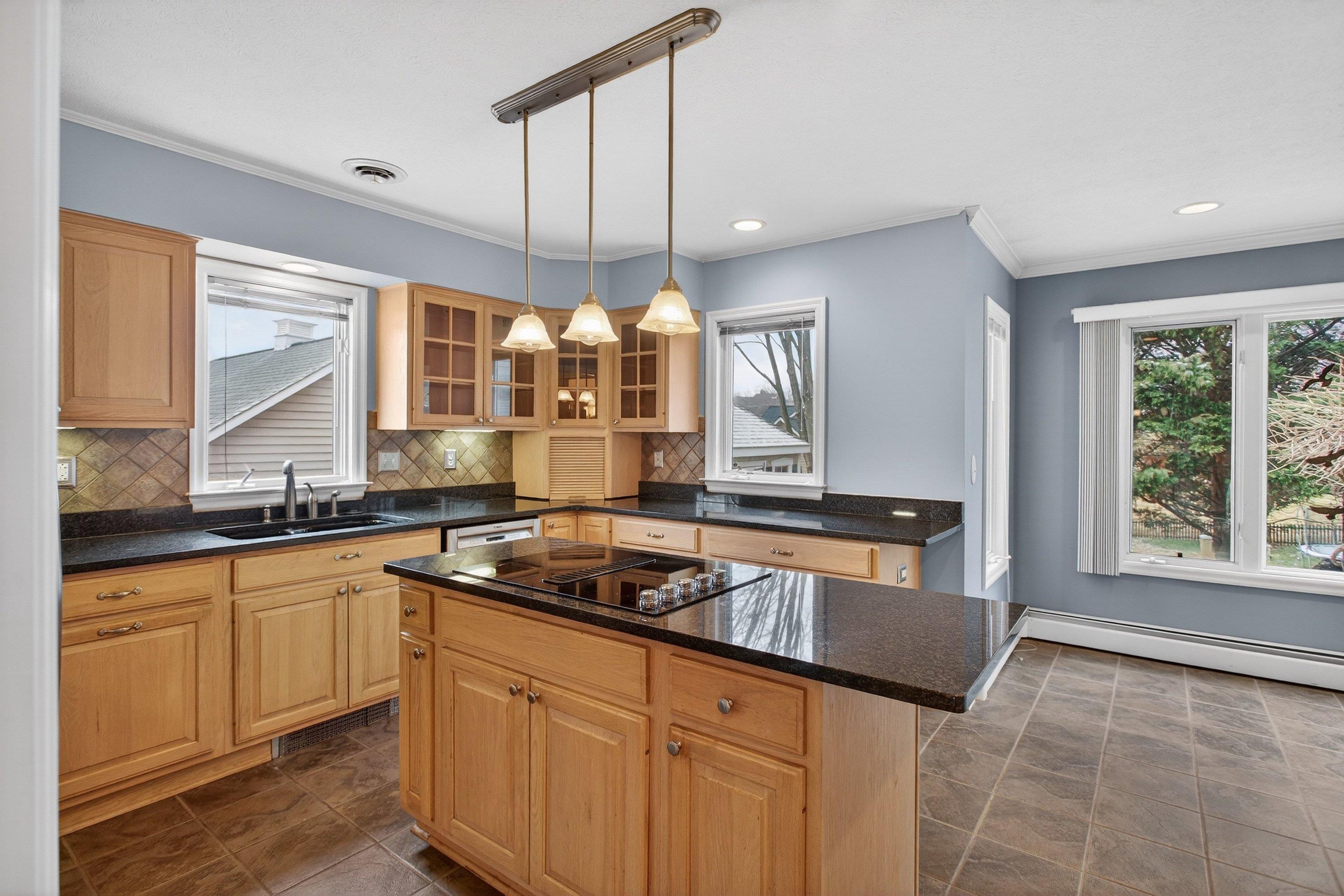 The large kitchen is located near the rear of the home and features ceramic tile flooring, granite counter-tops, wooden cabinetry, recessed lighting, and stainless steel appliances.