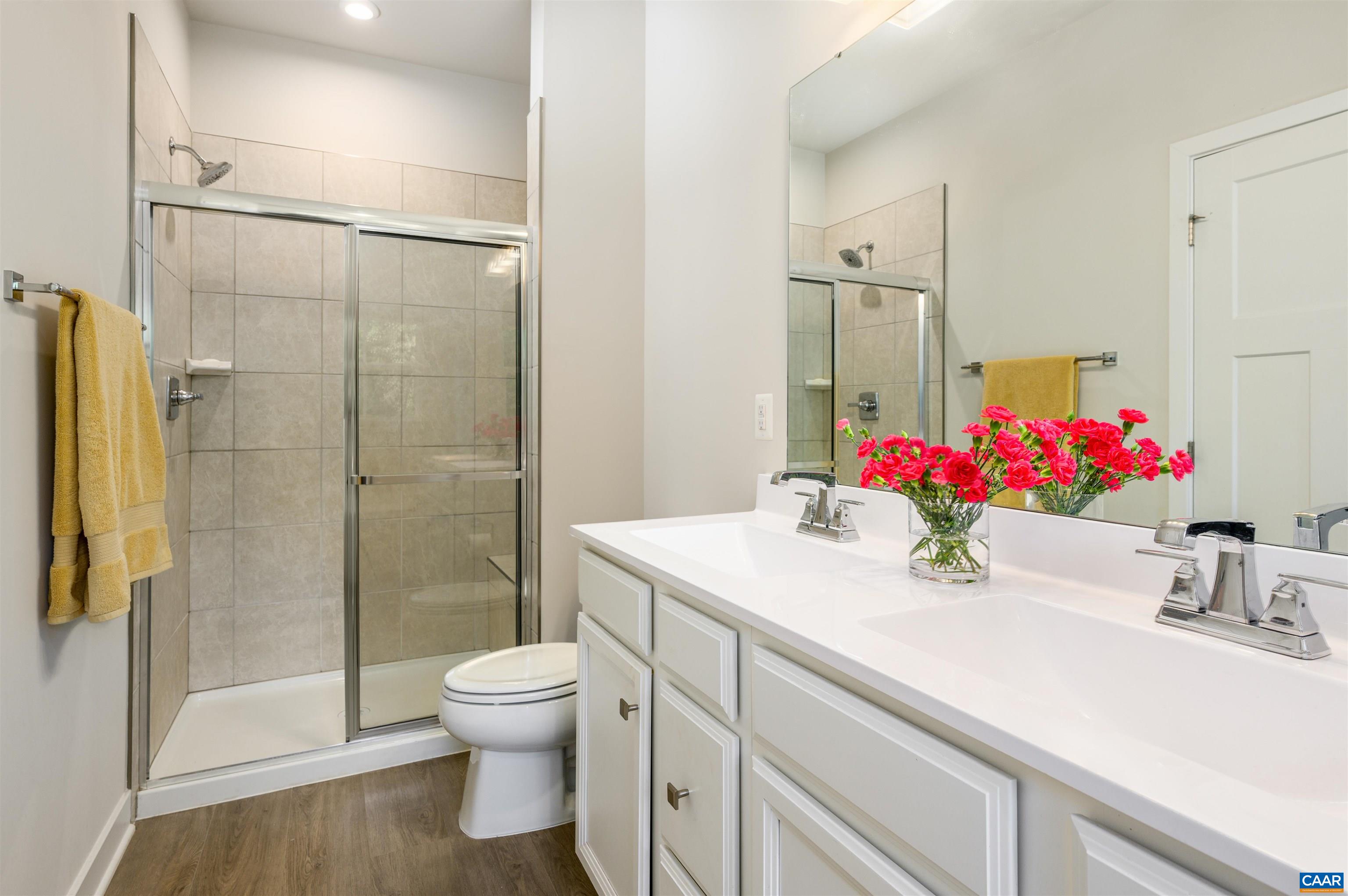 Tiled walk-in shower with glass enclosure and updated fixtures, offering a clean and modern feel.