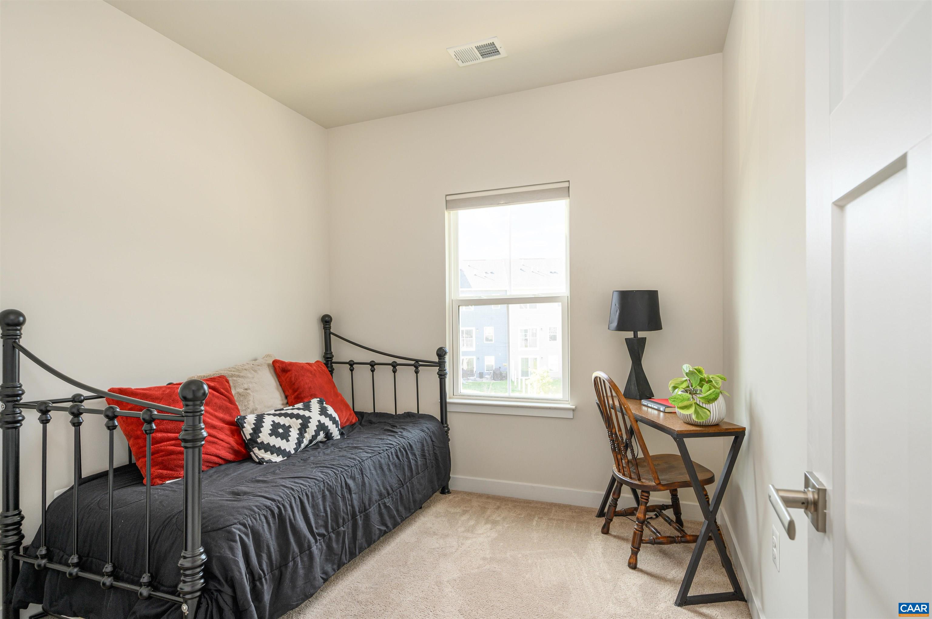 Comfortable secondary bedroom with neutral tones, blackout shades, and flexible use as guest space or home office.