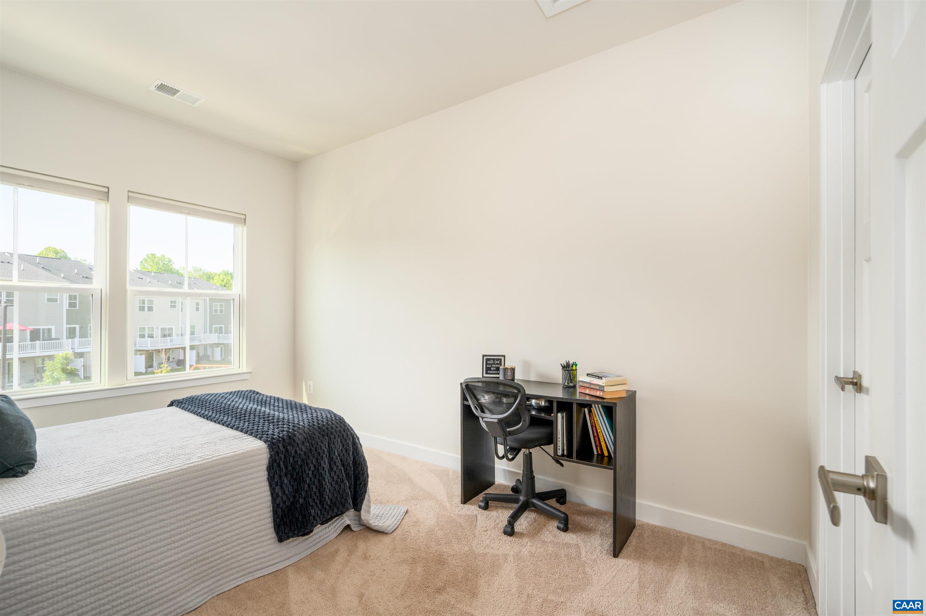 Comfortable secondary bedroom with neutral tones, blackout shades, and flexible use as guest space or home office.