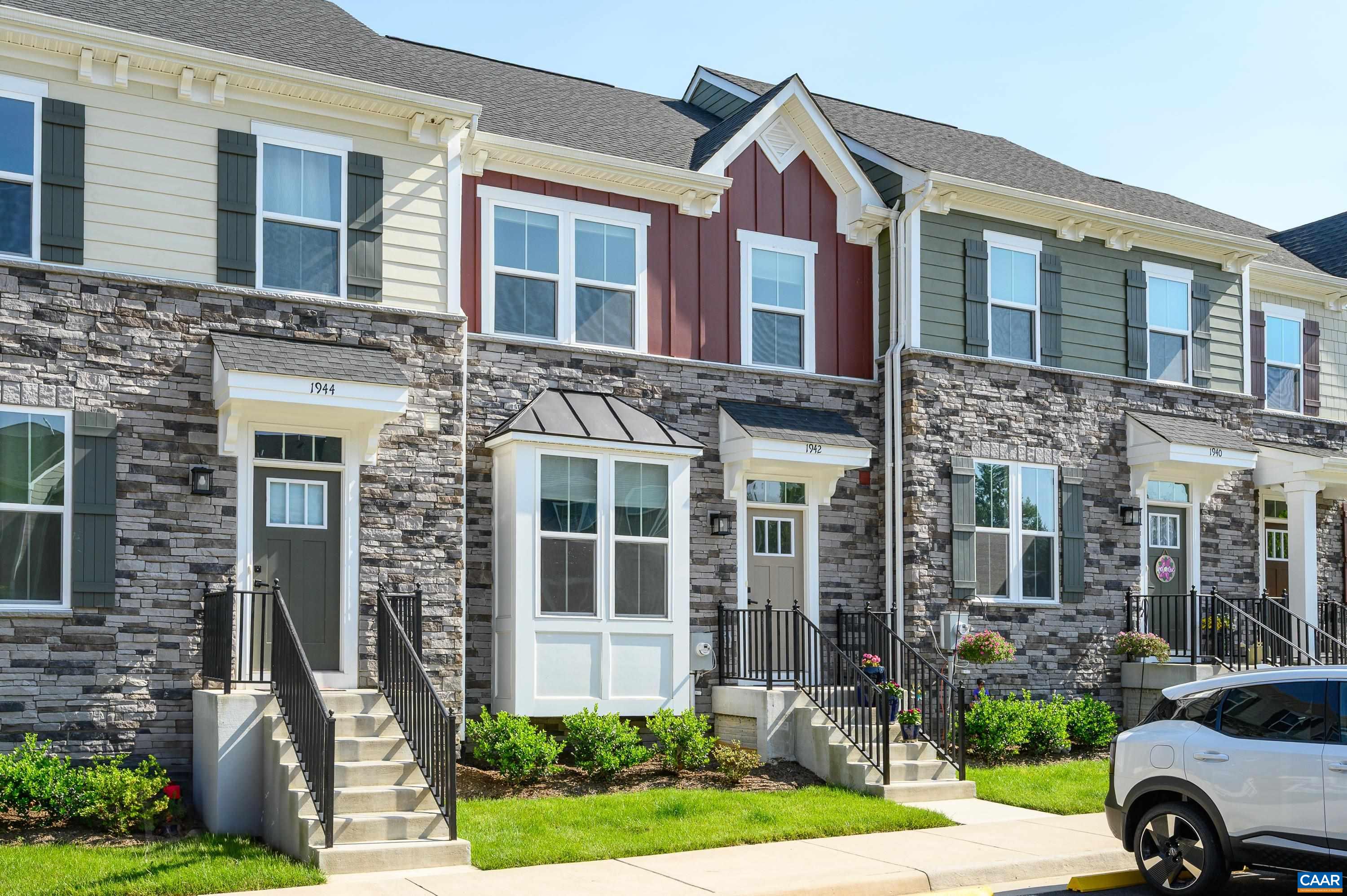 Attractive townhome exterior with stone accents, colorful red siding, and charming front entry with private staircase and landscaped details.
