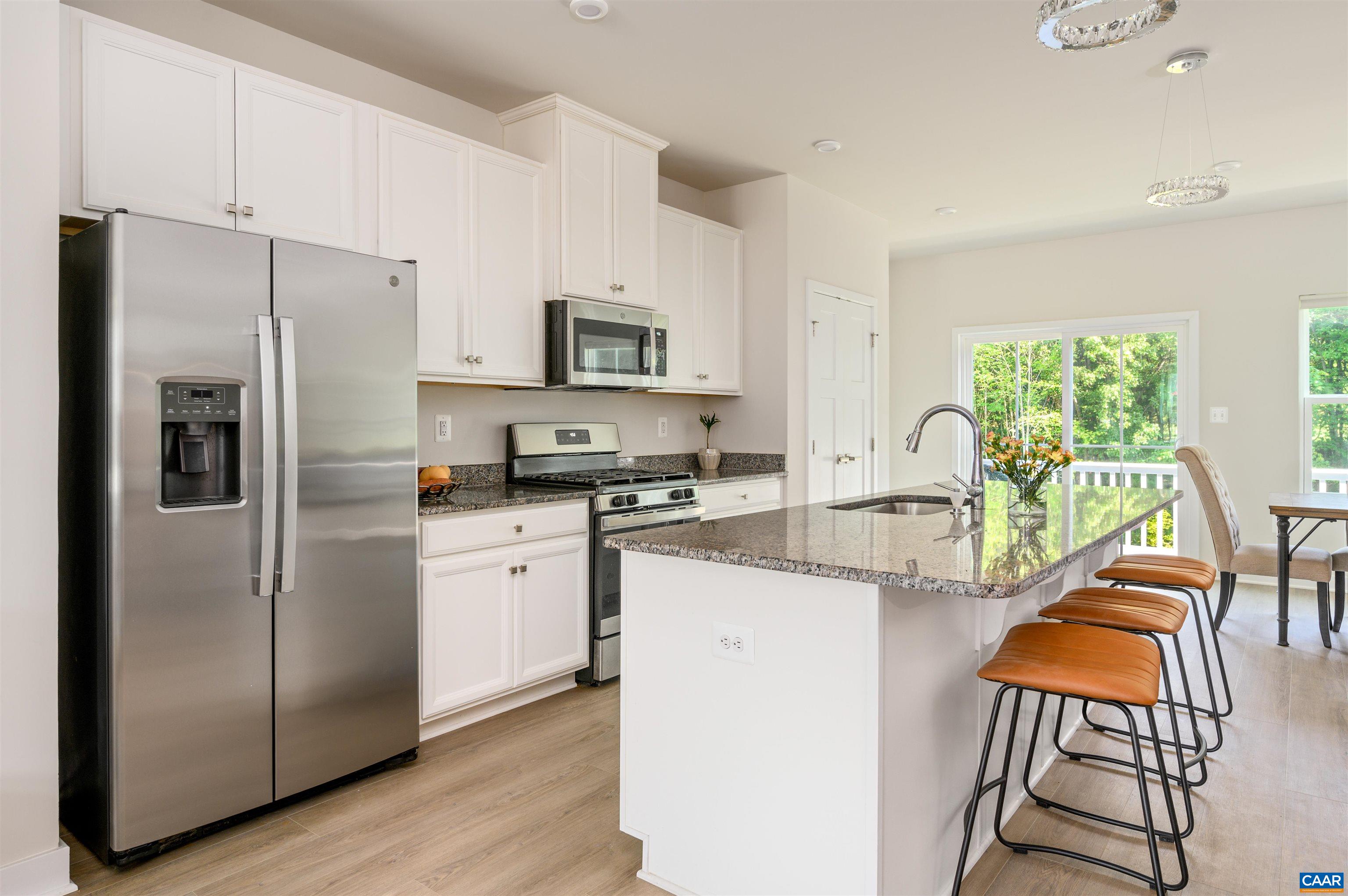 Well-appointed kitchen with granite countertops, stainless steel appliances, gas range, and large island with bar seating.